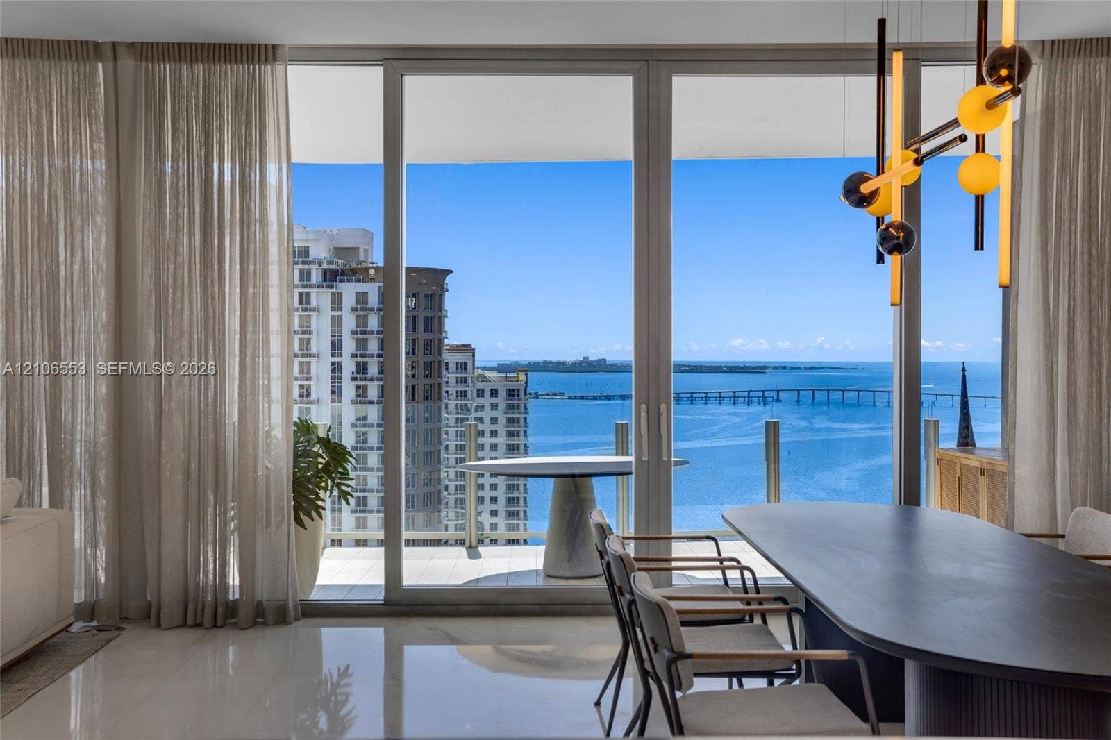 300 Biscayne Boulevard Way, #3002E, Miami, FL 33131 Floor-to-ceiling glass sliding doors, polished tile flooring, balcony with glass railing, and modern multi-bulb statement lighting