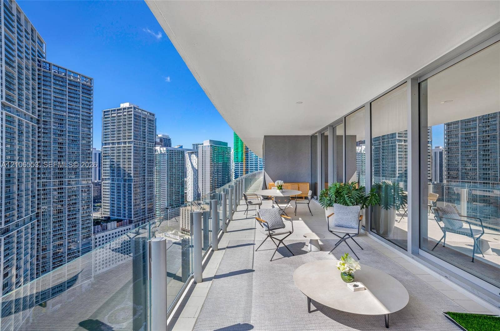 300 Biscayne Boulevard Way, #3002E, Miami, FL 33131 Expansive covered balcony featuring glass panel railings, concrete-finish flooring, and floor-to-ceiling glass wall panels
