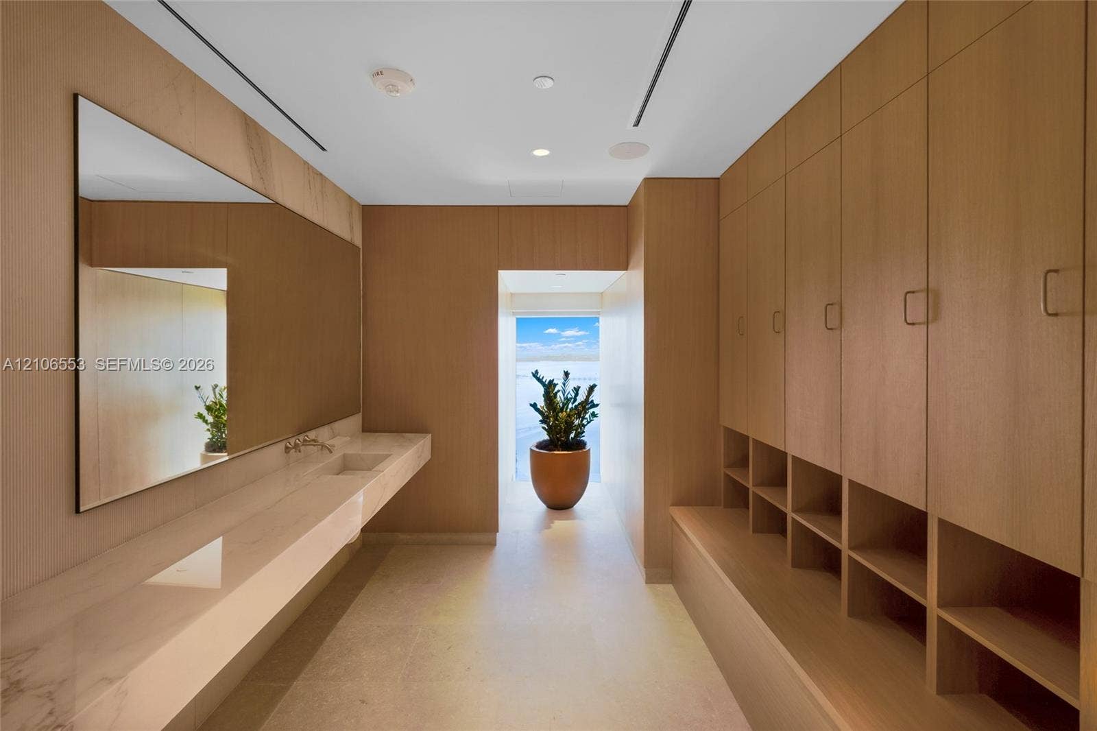 300 Biscayne Boulevard Way, #3002E, Miami, FL 33131 Full-height wood-finish cabinetry with open cubbies, floating stone-surface vanity with an integrated sink, wall-mounted faucet, and a large rectangular mirror