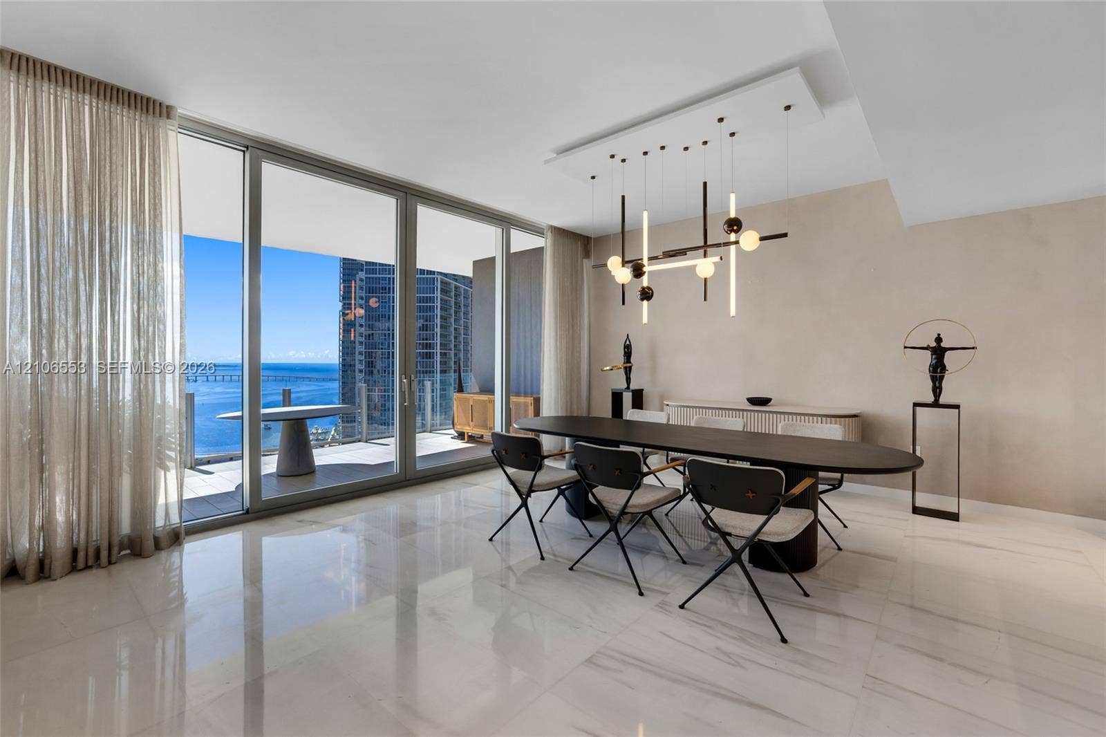 300 Biscayne Boulevard Way, #3002E, Miami, FL 33131 Floor-to-ceiling glass sliding doors, polished stone-finish flooring, custom modern linear pendant lighting, and an expansive covered balcony
