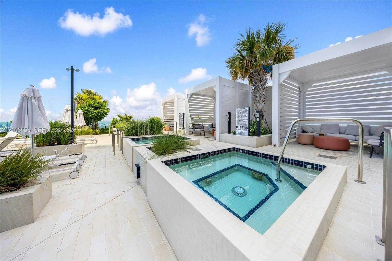 300 Biscayne Boulevard Way, #3002E, Miami, FL 33131 Rooftop terrace featuring built-in spa with tile surround, white pergolas, stone-finish decking, and integrated landscaping planters