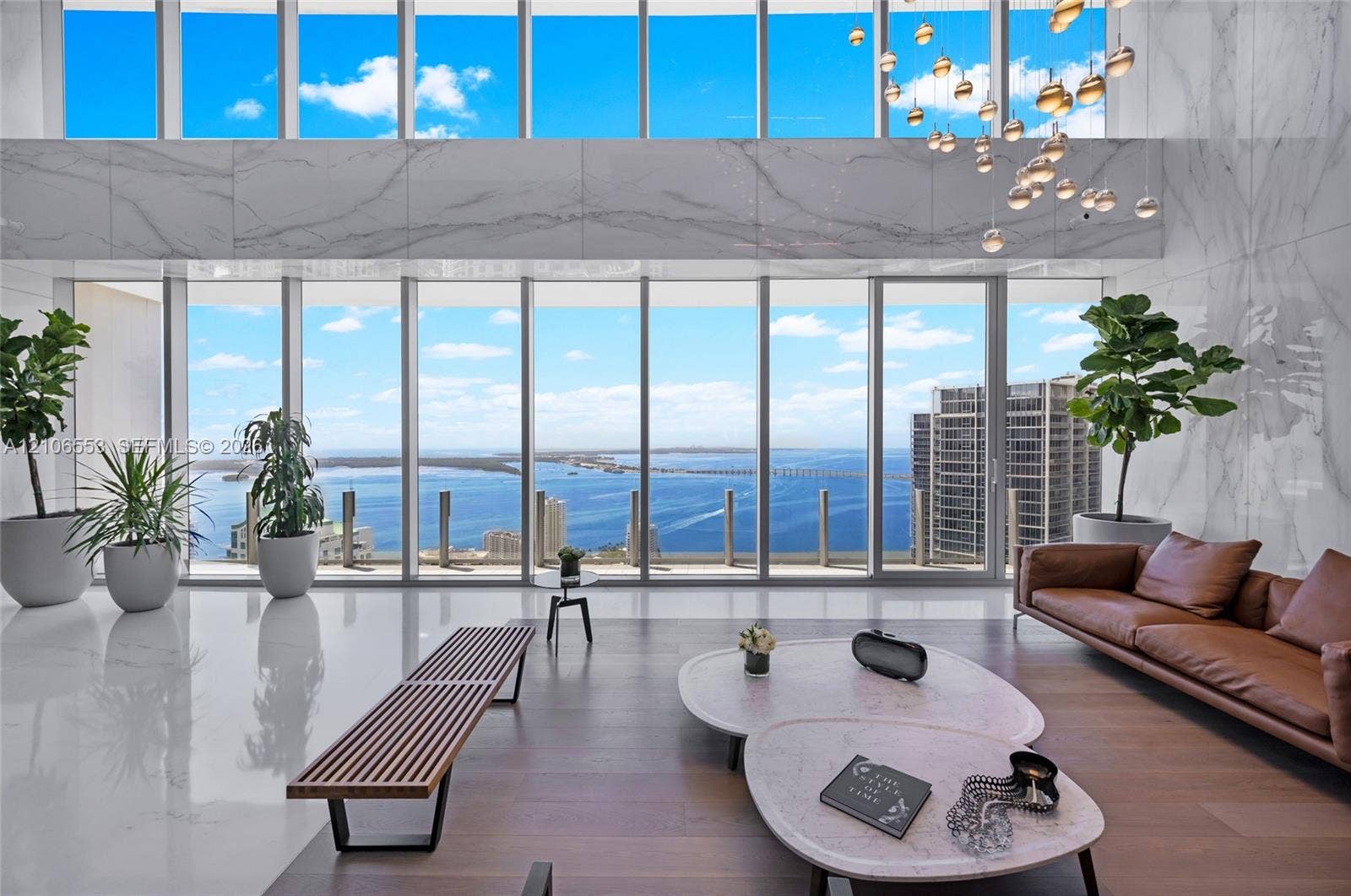 300 Biscayne Boulevard Way, #3002E, Miami, FL 33131 Double-height floor-to-ceiling windows, stone-clad accent wall, polished stone flooring, wood-finish flooring, and multi-tiered glass pendant lighting