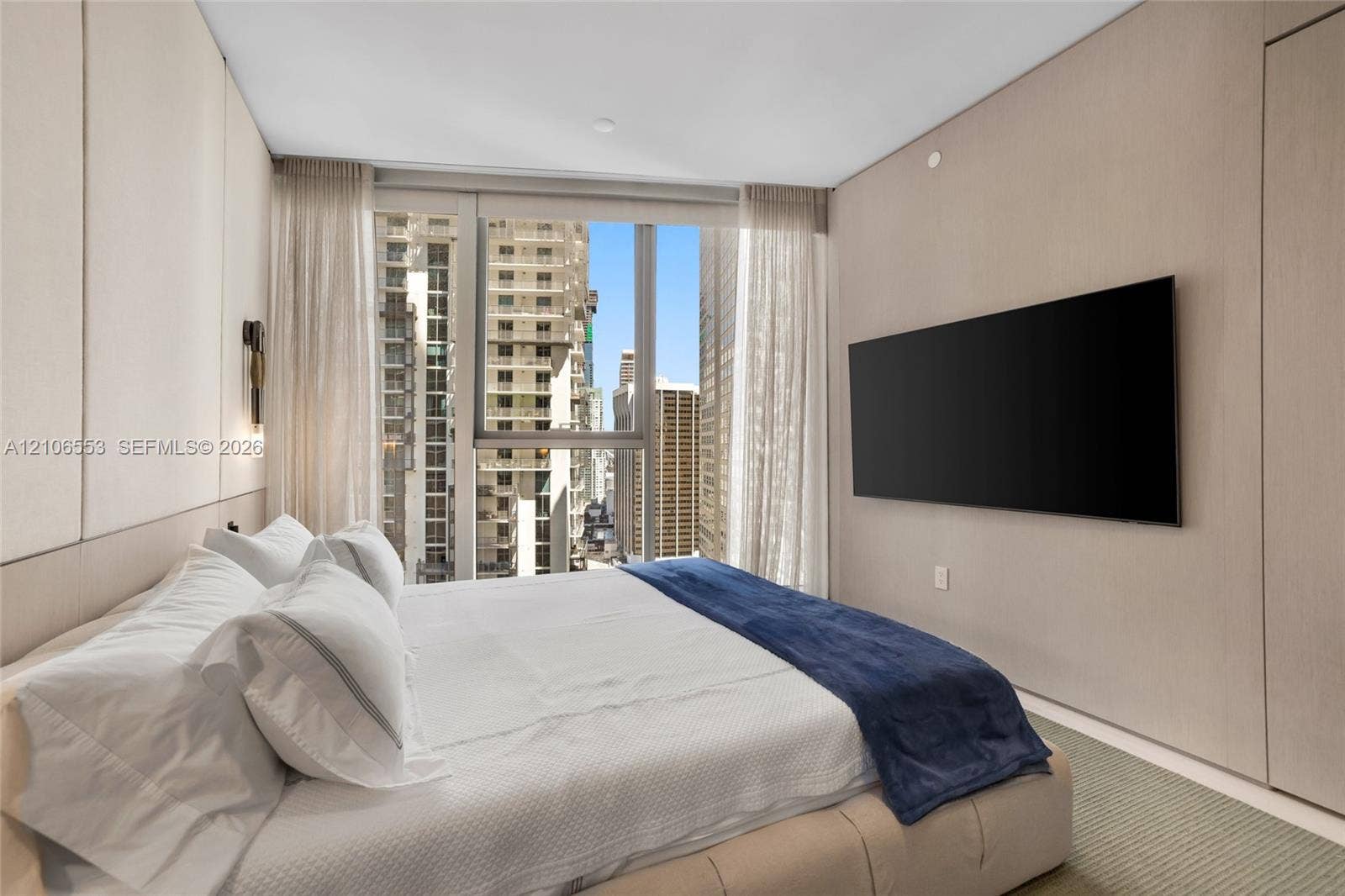 300 Biscayne Boulevard Way, #3002E, Miami, FL 33131 Floor-to-ceiling windows featuring urban scenery, custom wood-paneled wall treatment, integrated wall-mounted lighting, and neutral carpeting