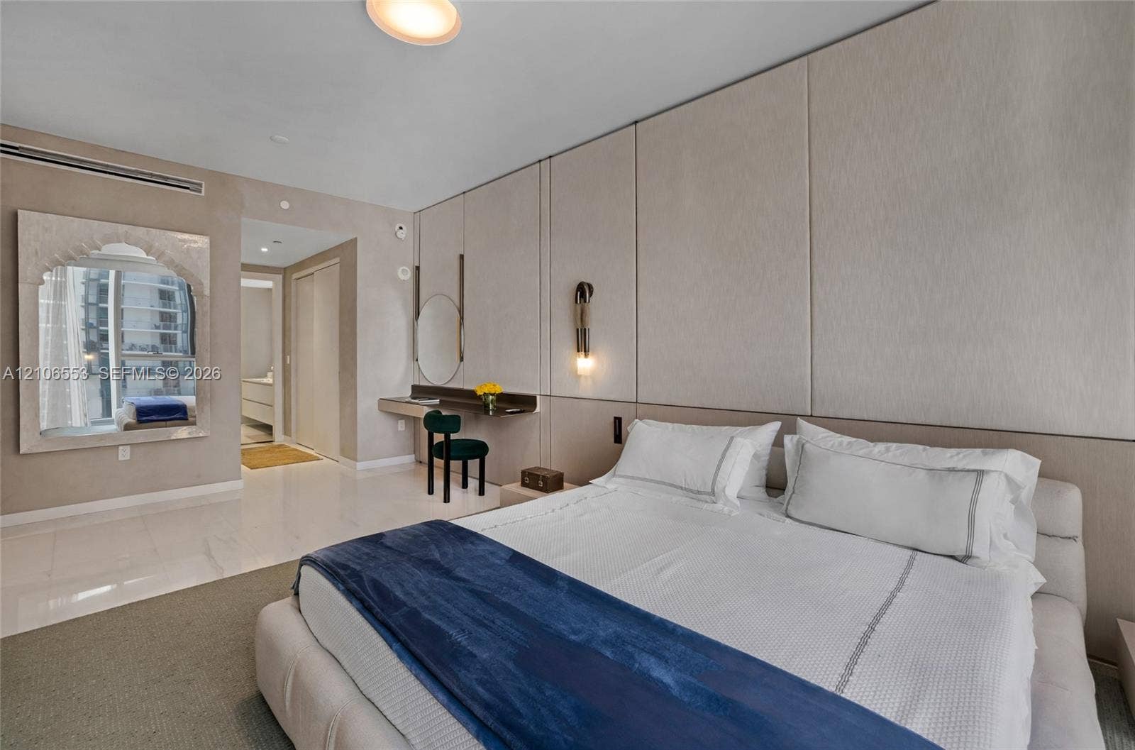 300 Biscayne Boulevard Way, #3002E, Miami, FL 33131 Floor-to-ceiling paneled wall, custom built-in vanity, arched wall mirror with decorative frame, recessed ceiling lighting, and polished stone flooring