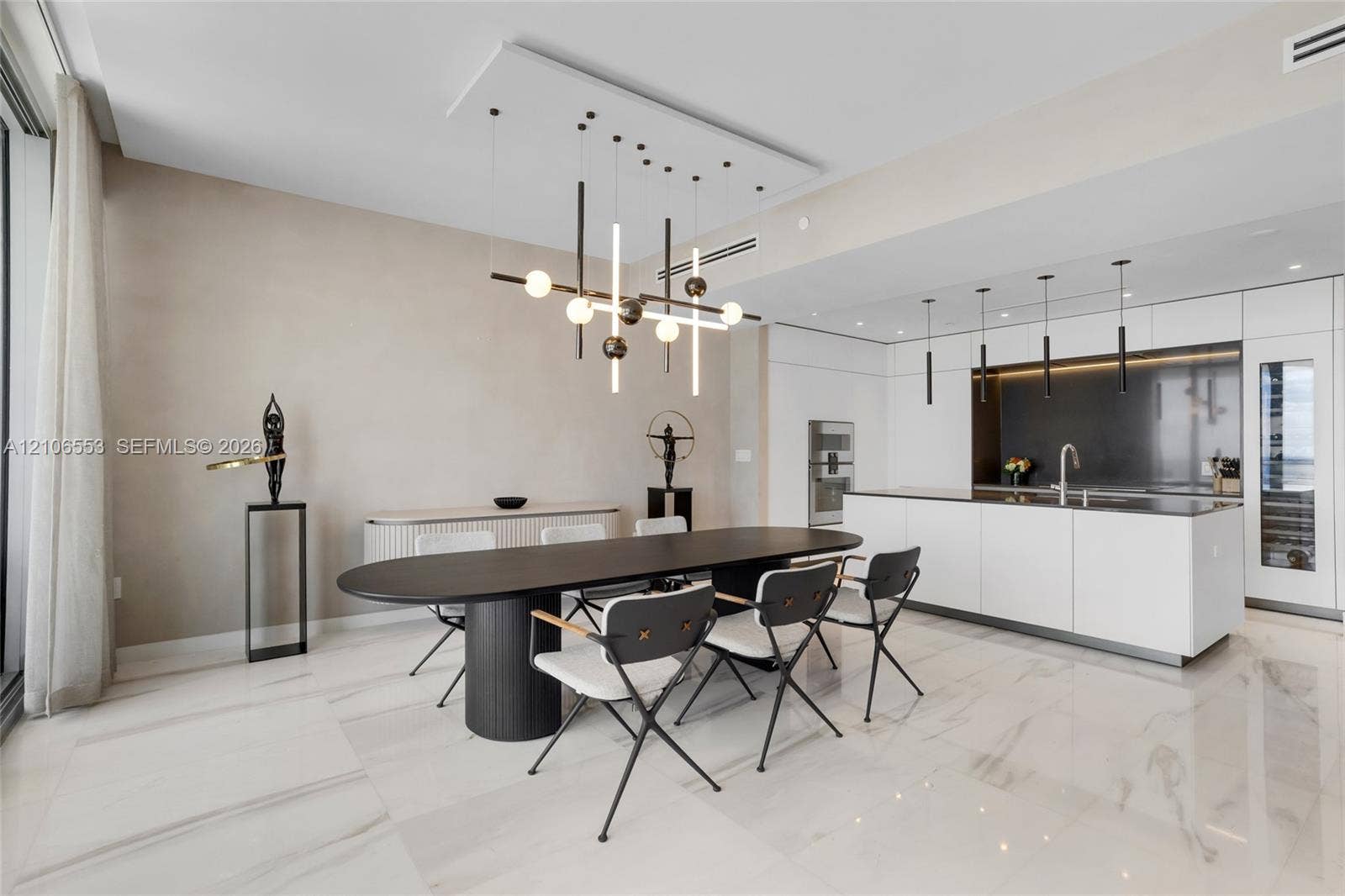 300 Biscayne Boulevard Way, #3002E, Miami, FL 33131 Open-concept interior featuring large-format stone flooring, a center island with integrated sink, built-in panel-ready appliances, and a geometric chandelier with linear and spherical lighting elements