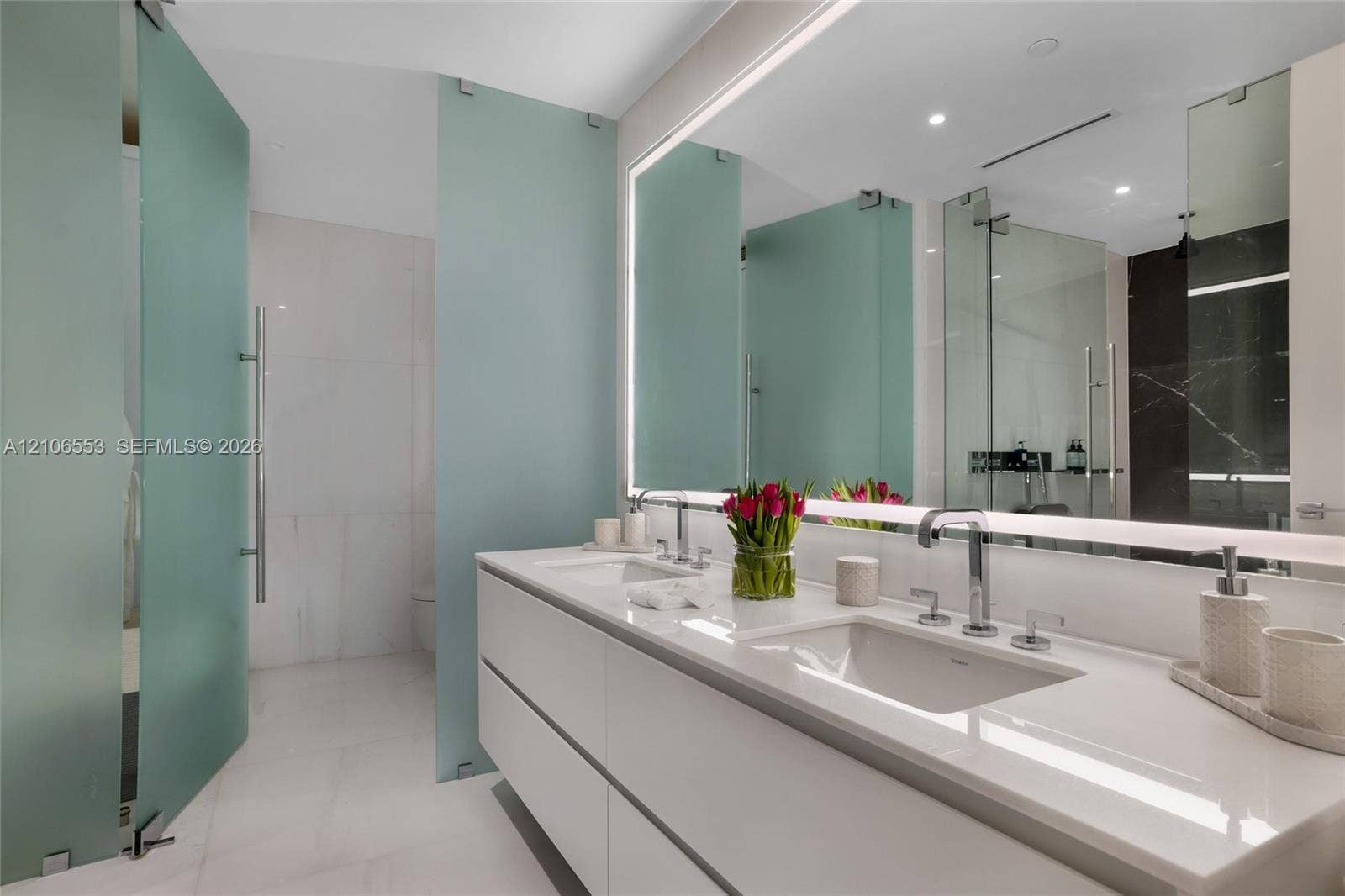 300 Biscayne Boulevard Way, #3002E, Miami, FL 33131 Floating dual-sink vanity with a solid surface countertop, integrated LED-backlit mirror, and frosted glass privacy partitions