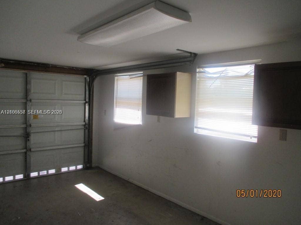 Enclosed garage featuring a metal sectional door, ceiling-mounted light fixture, and wall-mounted cabinetry