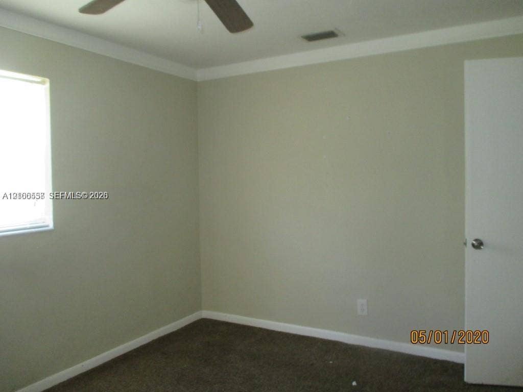 Neutral wall tones, carpeted flooring, and a ceiling fan with integrated lighting