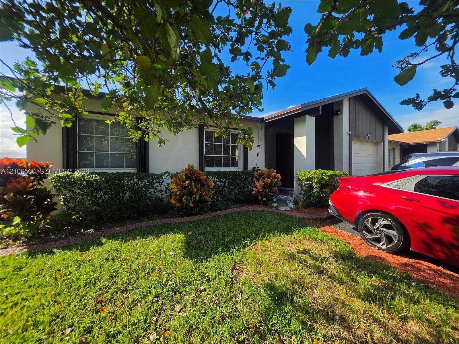 9550 W Elm Lane, Miramar, FL 33025 Single-story residence featuring a stucco facade, divided-lite grid windows, covered entryway, and attached garage