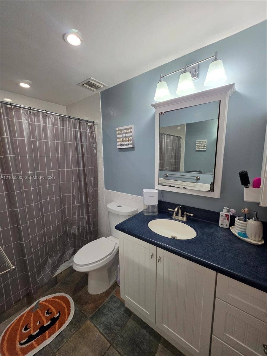 9550 W Elm Lane, Miramar, FL 33025 Bathroom vanity featuring a solid-surface countertop, integrated basin, white cabinetry, and three-light vanity fixture above a medicine cabinet