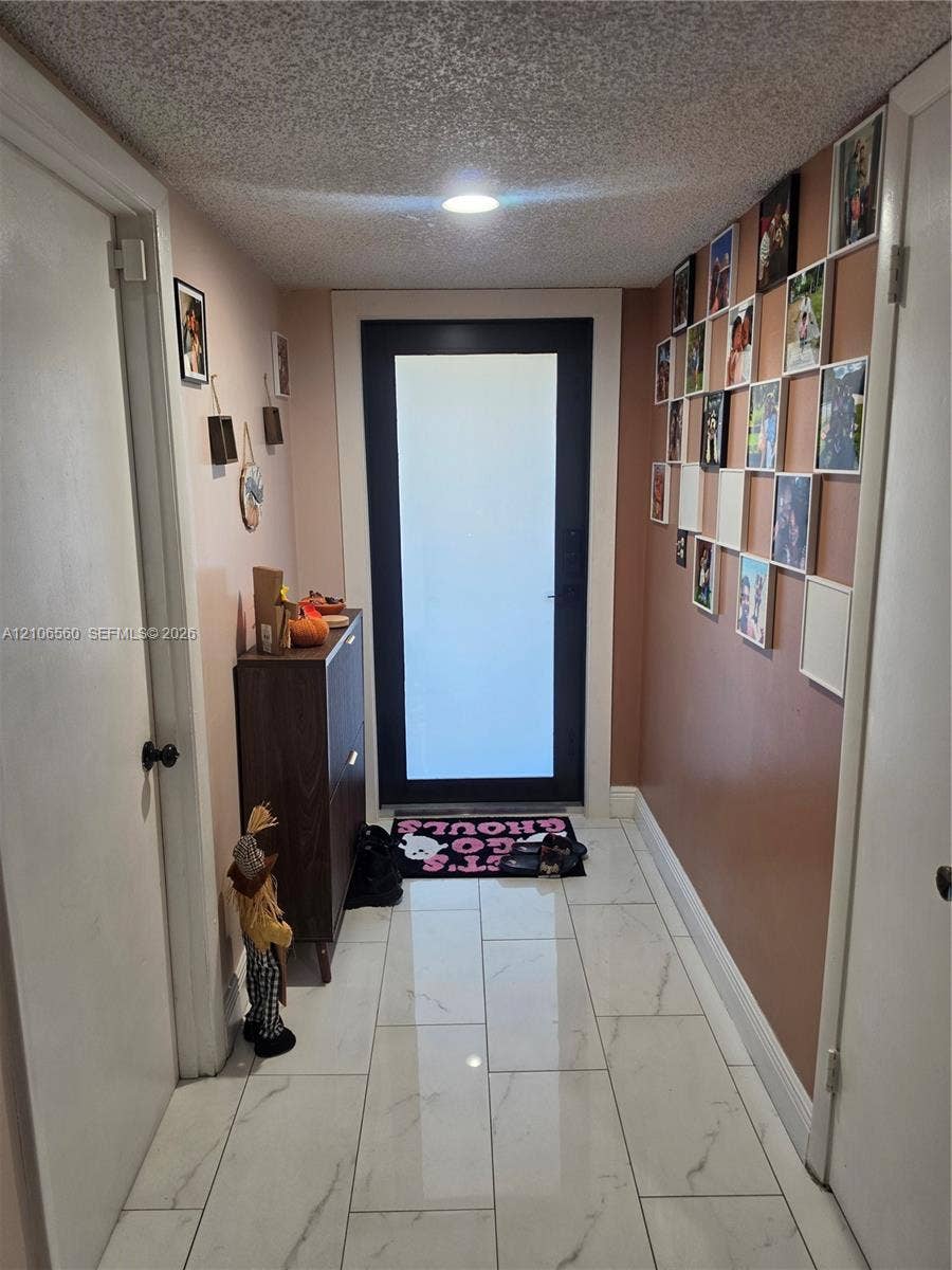 9550 W Elm Lane, Miramar, FL 33025 Entryway featuring a black-framed door with a frosted glass panel, recessed ceiling lighting, and light-toned large-format tile flooring