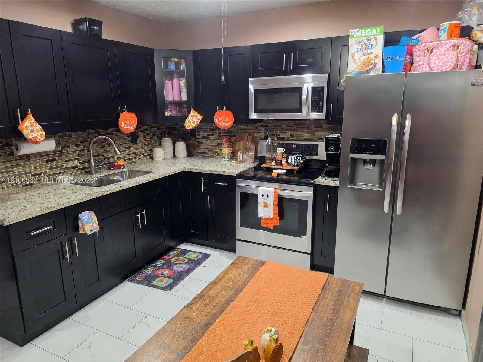 9550 W Elm Lane, Miramar, FL 33025 Kitchen featuring dark cabinetry, stone-finish countertops, stainless steel appliances, and a glass-tiled backsplash
