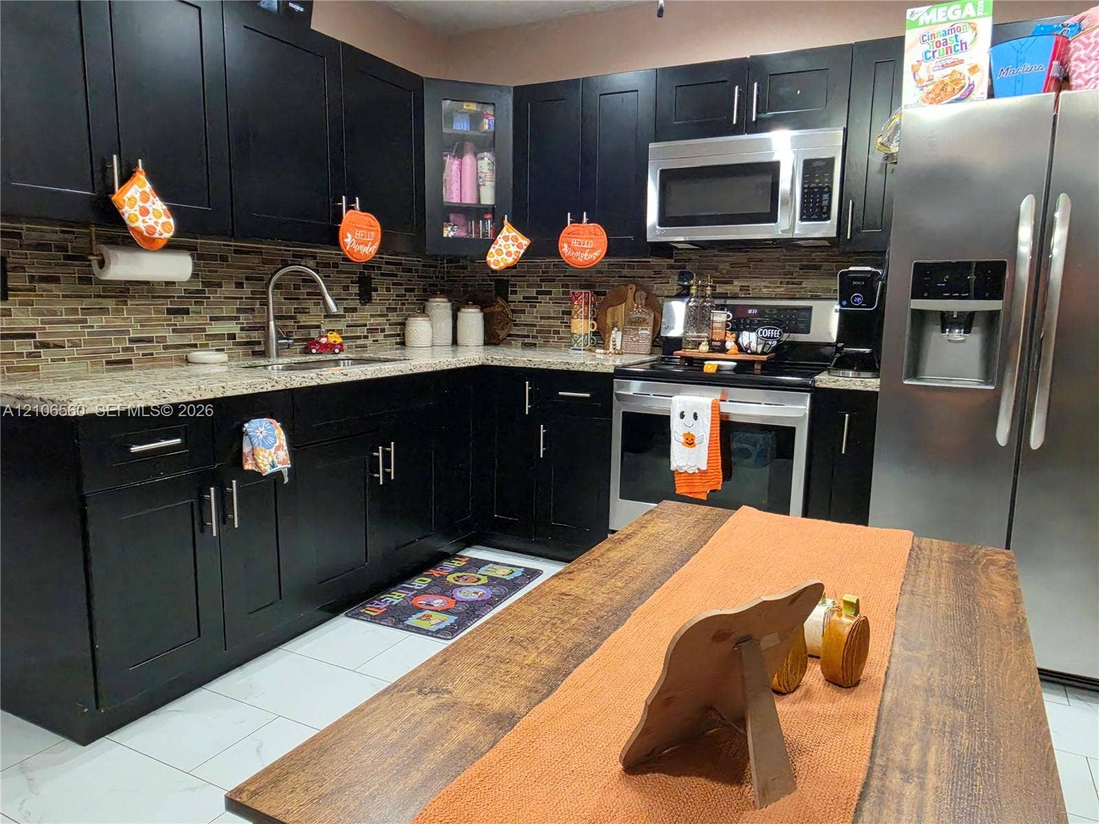 9550 W Elm Lane, Miramar, FL 33025 Kitchen featuring black cabinetry, light-toned stone-look countertops, a mosaic tile backsplash, stainless steel appliances, and tile flooring