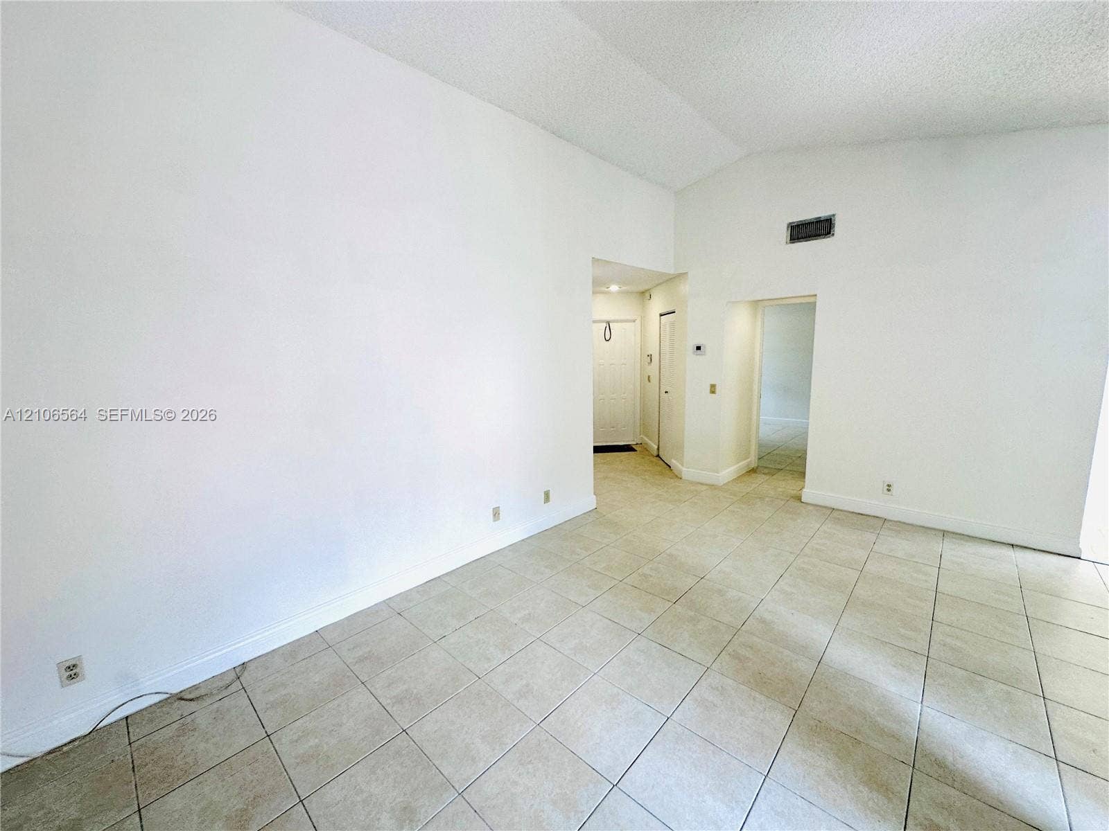 Vaulted ceilings, large-format neutral tile flooring, and crisp white wall finishes
