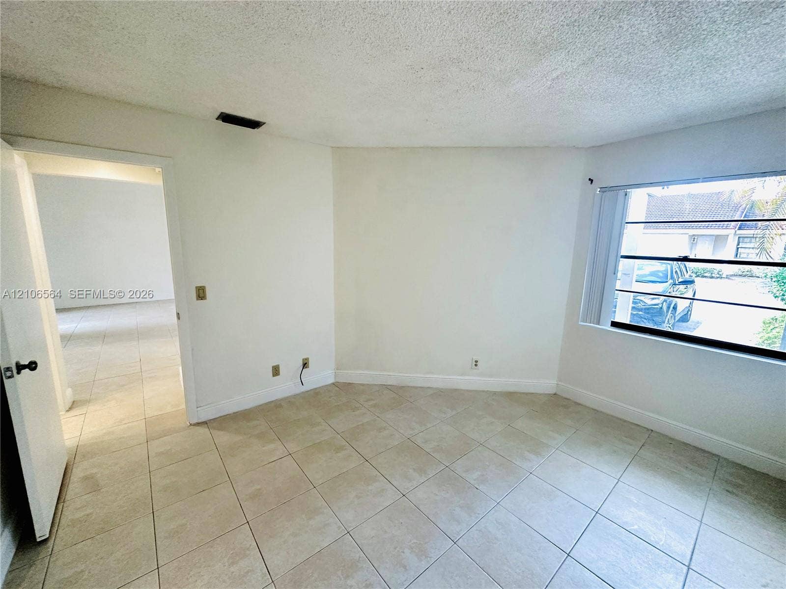 Interior space featuring neutral tile flooring, textured ceiling, and a multi-pane horizontal window
