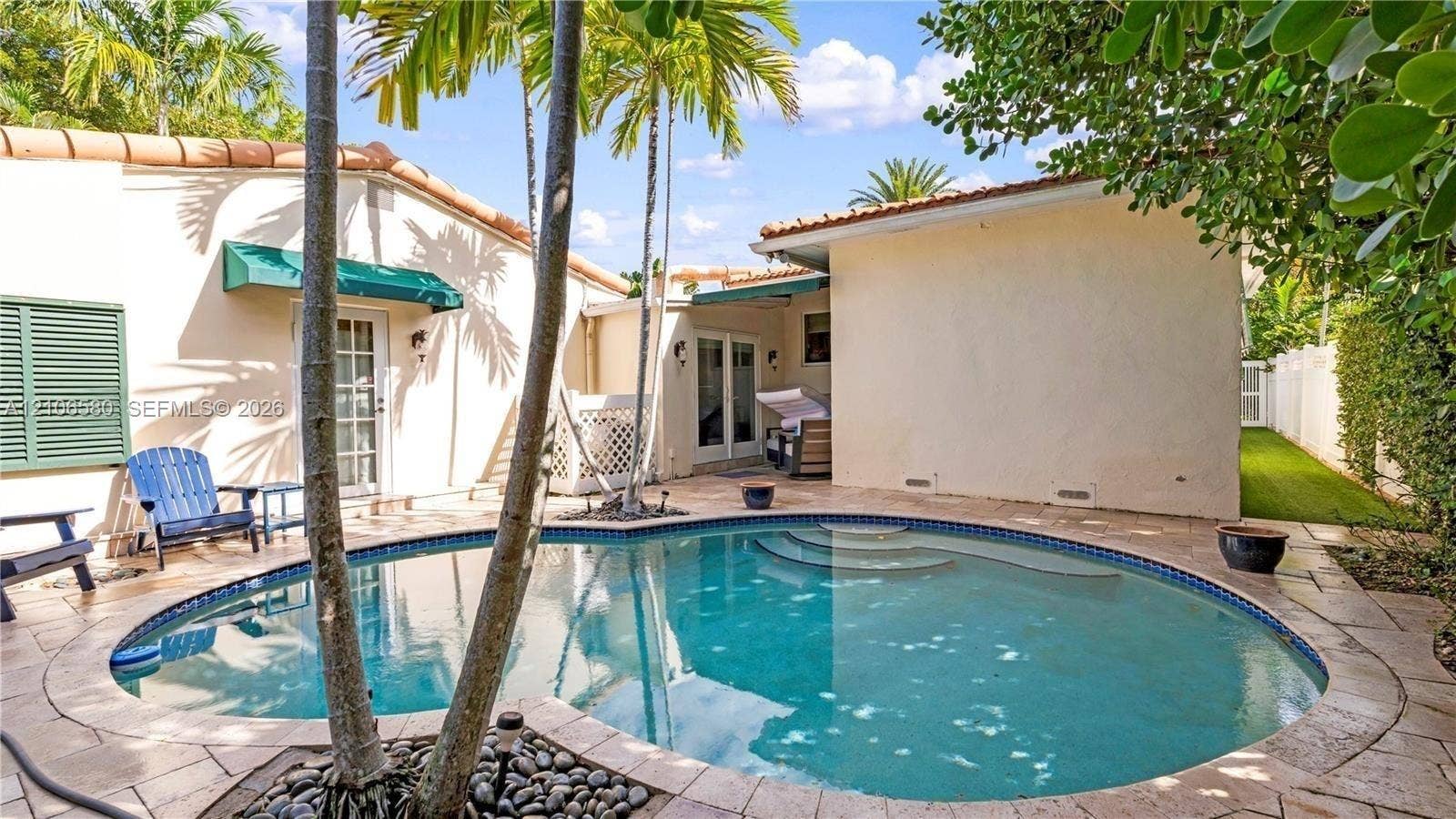 623 NE 17th Way, Fort Lauderdale, Fort Lauderdale, FL 33304 Exterior courtyard featuring a curved swimming pool, natural stone pool deck, built-in steps, and palm trees