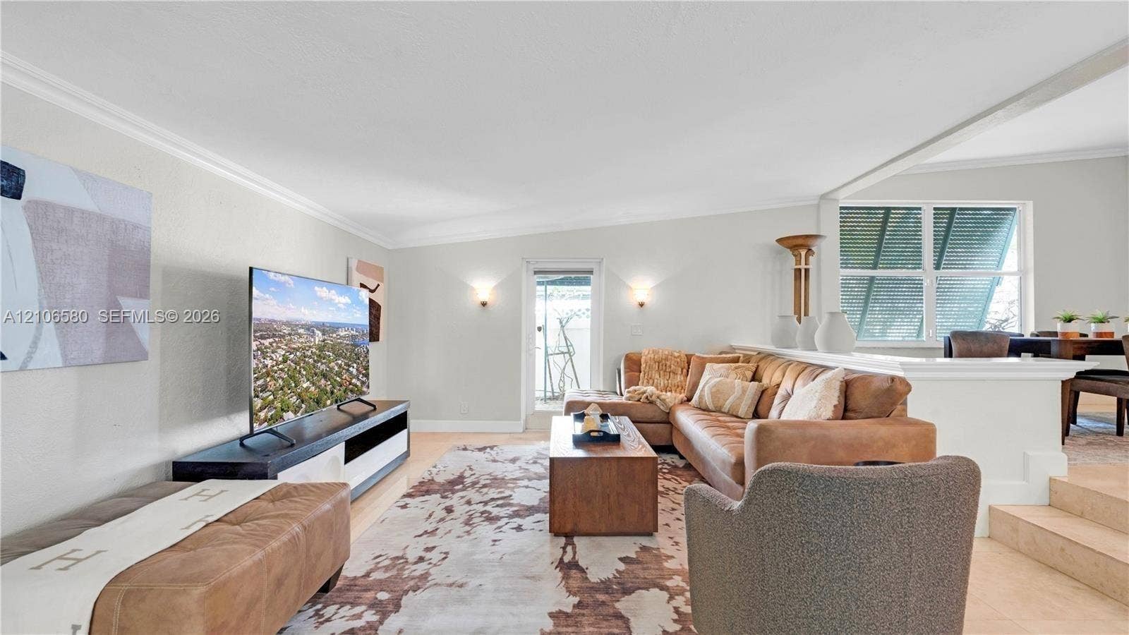 623 NE 17th Way, Fort Lauderdale, Fort Lauderdale, FL 33304 Living area featuring wall-mounted sconce lighting, crown molding, a half-wall partition, and multi-level floor elevation