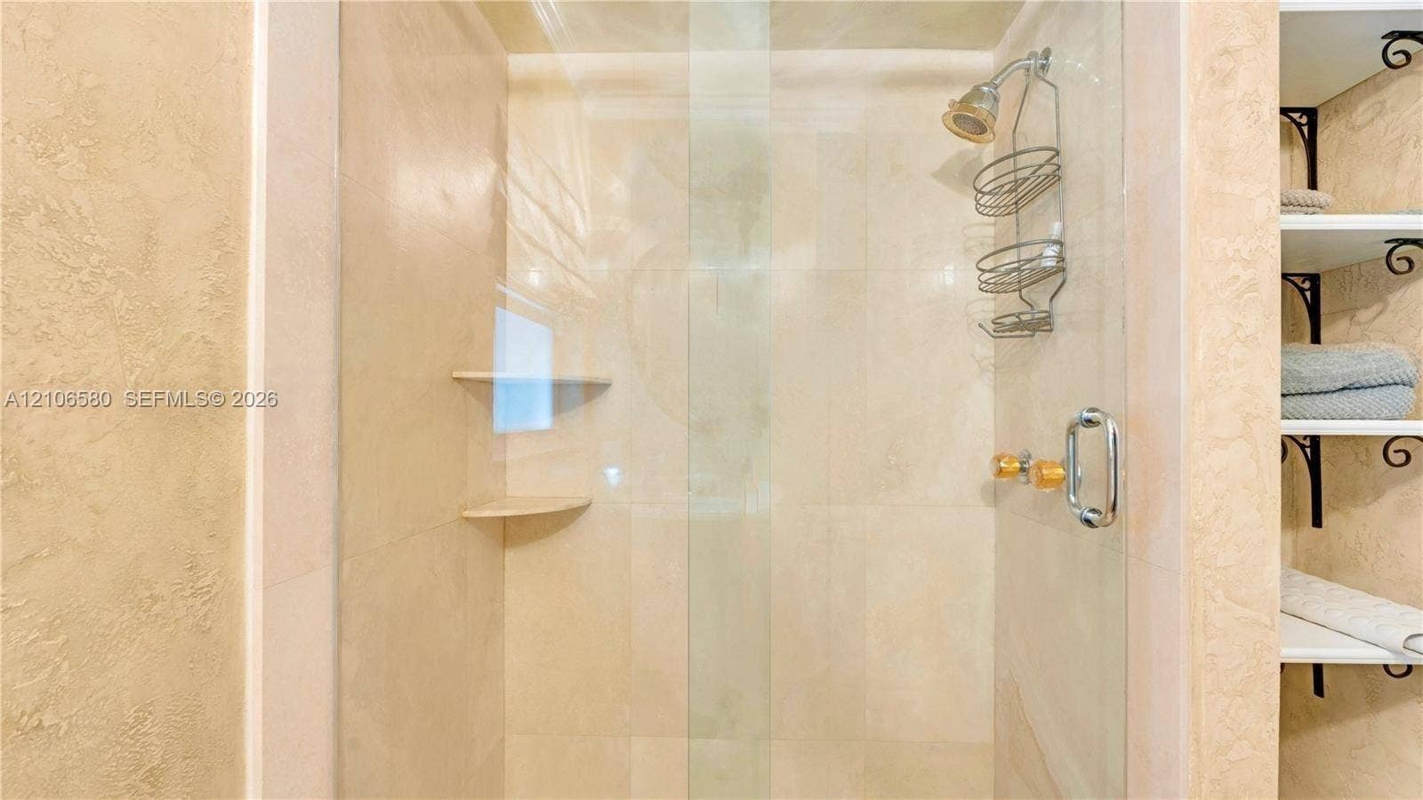 623 NE 17th Way, Fort Lauderdale, Fort Lauderdale, FL 33304 Walk-in shower featuring floor-to-ceiling stone-style tile, clear glass enclosure, built-in shelving, and metallic hardware