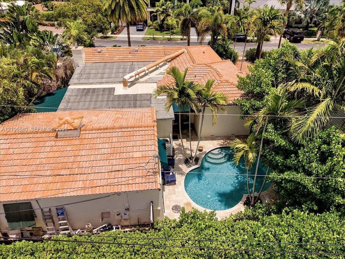 623 NE 17th Way, Fort Lauderdale, Fort Lauderdale, FL 33304 Aerial perspective of a property featuring a multi-section clay tile roof, a curved swimming pool, stone paver decking, and mature palm trees