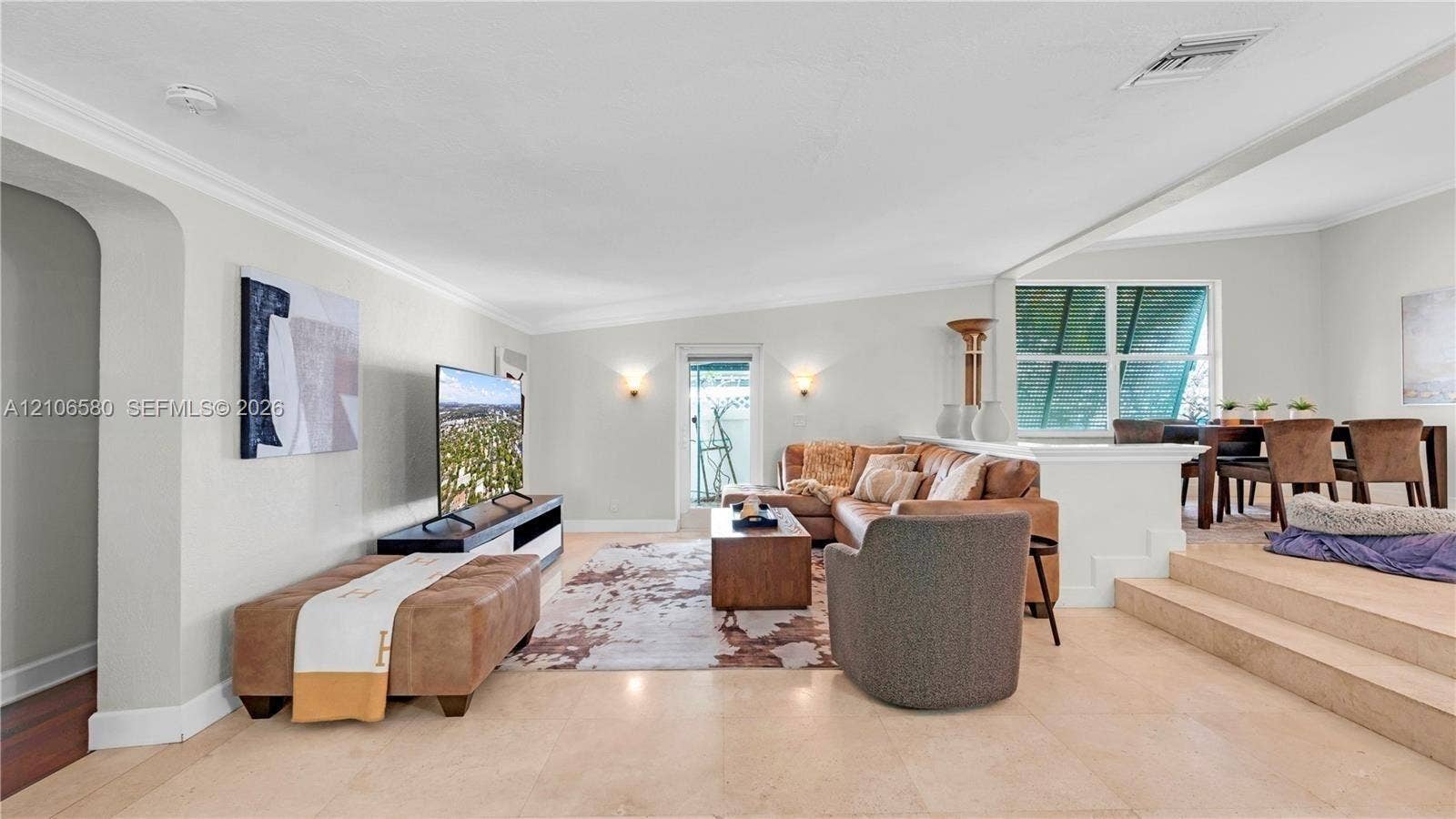 623 NE 17th Way, Fort Lauderdale, Fort Lauderdale, FL 33304 Open-concept floor plan featuring light-toned tile flooring, recessed crown molding, arched entryways, and a multi-level layout with a carpeted elevated platform