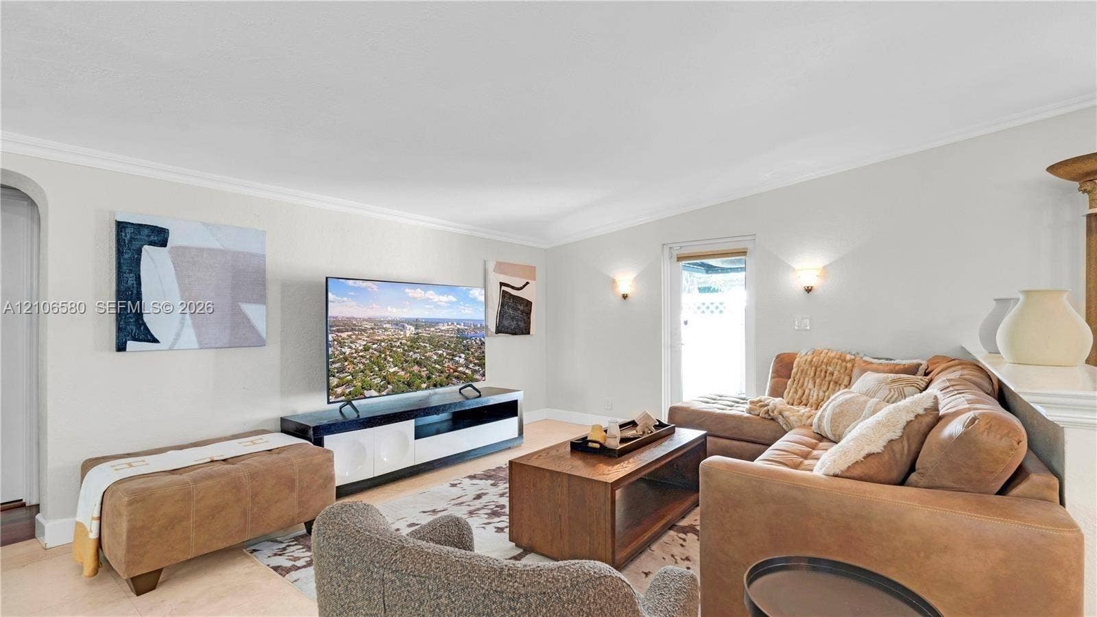 623 NE 17th Way, Fort Lauderdale, Fort Lauderdale, FL 33304 Living space featuring neutral wall paint, arched entry, crown molding, and wall-mounted sconce lighting