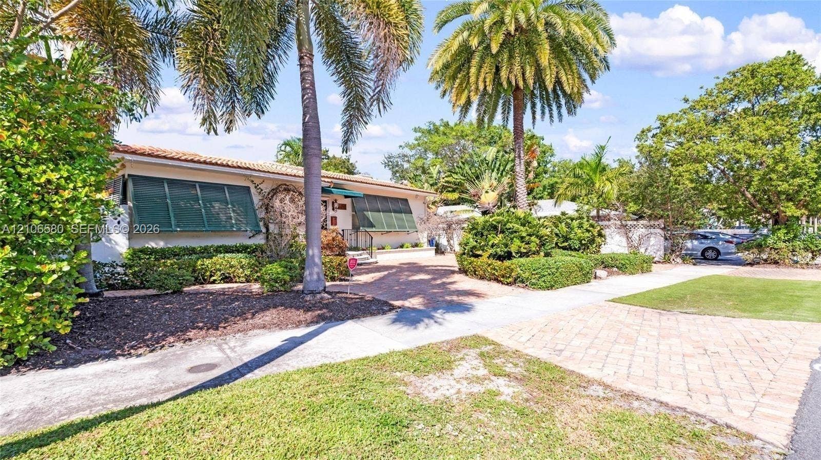 623 NE 17th Way, Fort Lauderdale, Fort Lauderdale, FL 33304 Single-story residence featuring a tile roof, decorative green shutters, paver driveway, and mature landscaping