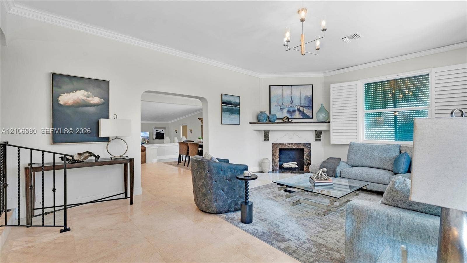 623 NE 17th Way, Fort Lauderdale, Fort Lauderdale, FL 33304 Living area featuring stone-finish flooring, a fireplace with a decorative mantel, crown molding, multi-light chandelier, and plantation shutters