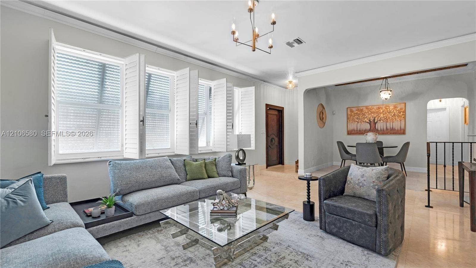 623 NE 17th Way, Fort Lauderdale, Fort Lauderdale, FL 33304 Living area featuring tile flooring, crown molding, multi-pane windows with plantation shutters, and a brass-finish chandelier