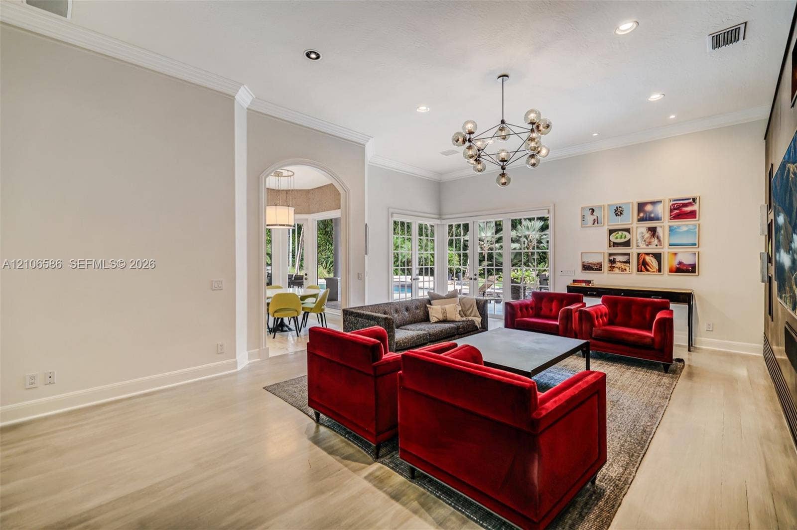 9325 SW 59th Place, Pinecrest, FL 33156 High-ceiling interior featuring wood-finish flooring, crown molding, multi-light geometric chandelier, and arched entryway