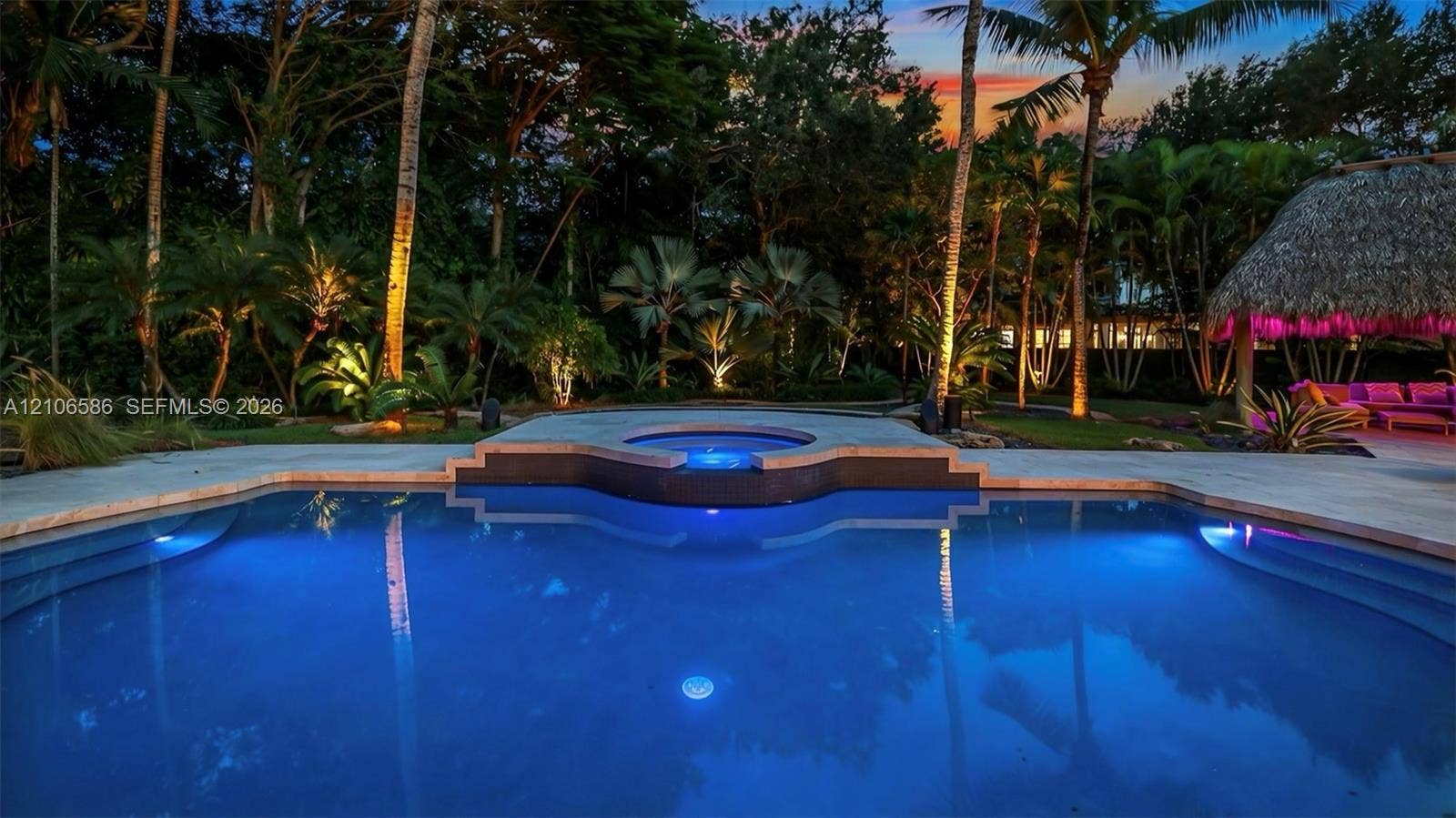 9325 SW 59th Place, Pinecrest, FL 33156 In-ground swimming pool with integrated elevated spa, stone-paver decking, thatch-roof cabana, and mature perimeter landscaping
