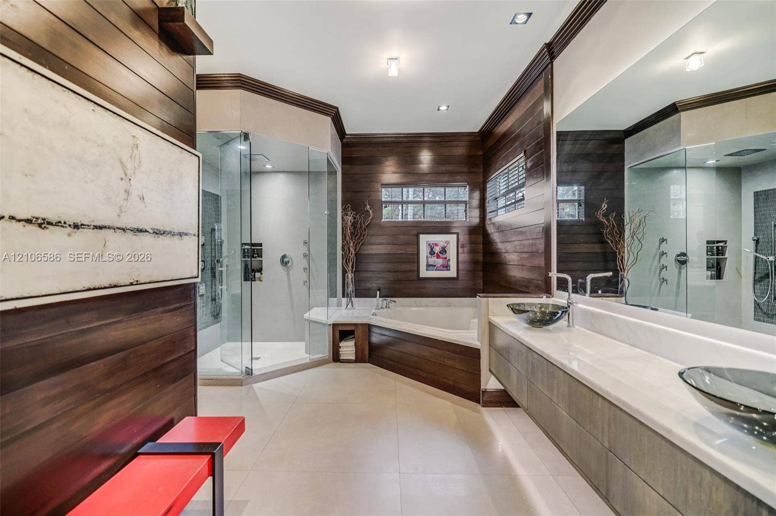 9325 SW 59th Place, Pinecrest, FL 33156 Custom bathroom featuring wood-paneled walls, a glass-enclosed shower, a jetted soaking tub, floating vanity with dual glass vessel sinks, and light-toned tile flooring