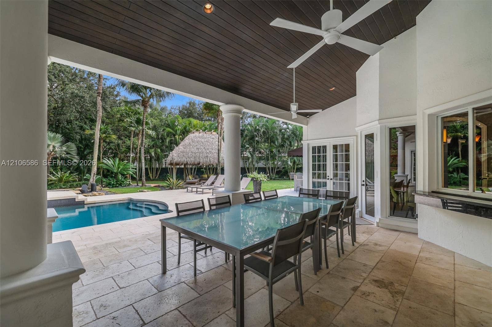 9325 SW 59th Place, Pinecrest, FL 33156 Covered patio featuring stone-tile flooring, a wood-paneled ceiling, ceiling fans, and structural columns