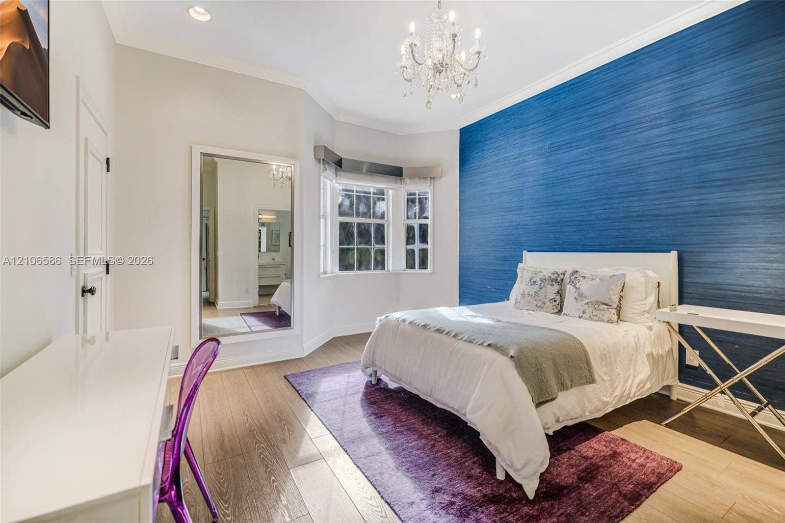 9325 SW 59th Place, Pinecrest, FL 33156 Bedroom featuring a deep blue textured accent wall, bay window, wood-finish flooring, recessed lighting, and a crystal chandelier