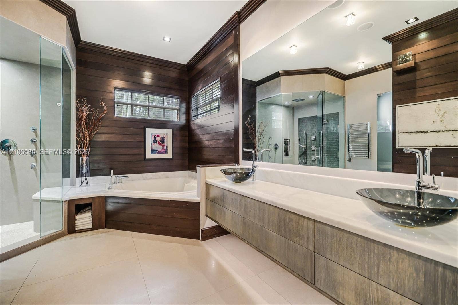 9325 SW 59th Place, Pinecrest, FL 33156 Dual vessel sinks with chrome faucets, stone-topped floating vanity, glass-enclosed shower, soaking tub, and horizontal wood-paneled walls