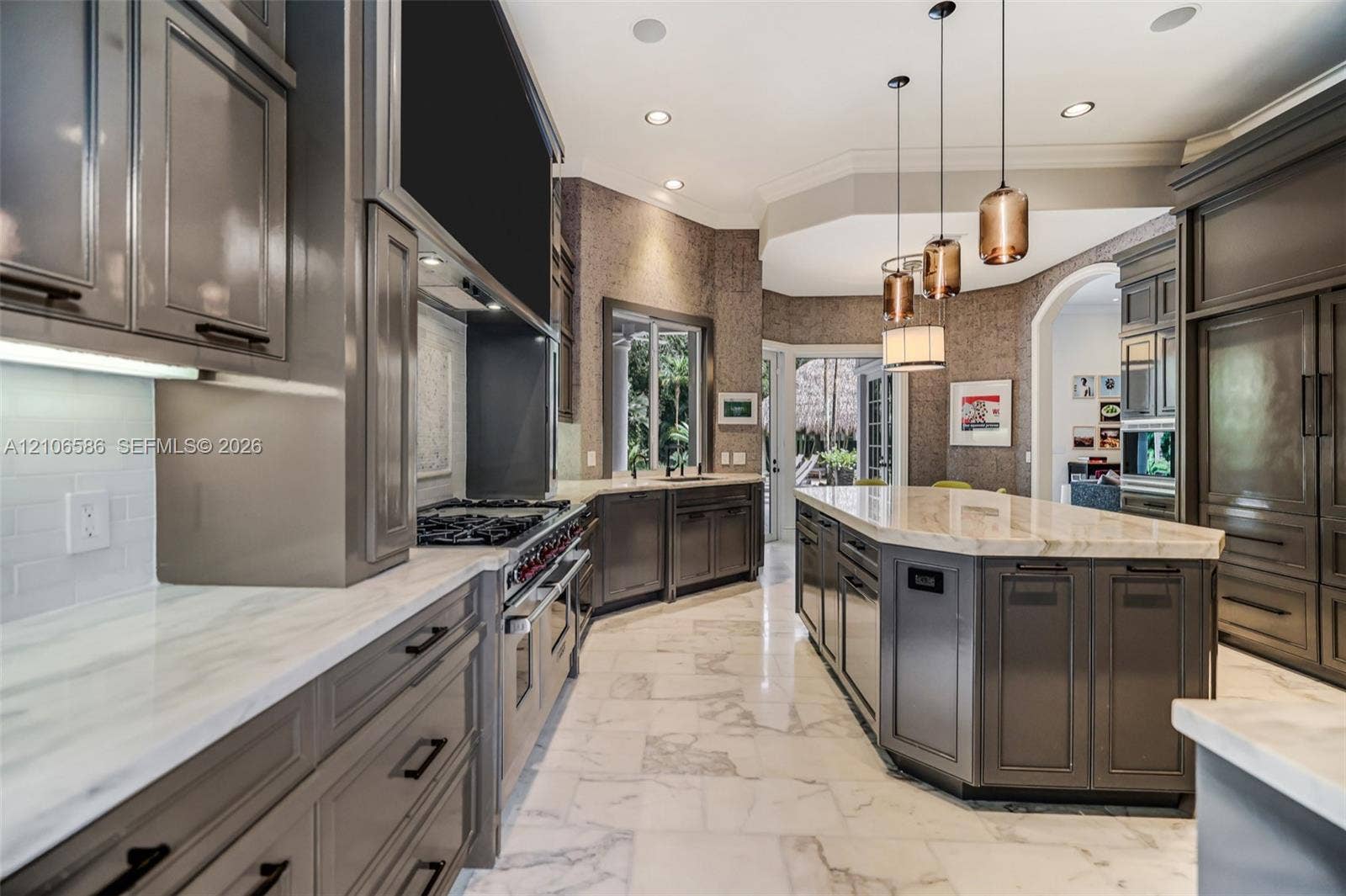 9325 SW 59th Place, Pinecrest, FL 33156 Kitchen featuring custom cabinetry, light-toned stone countertops, professional-grade range, large central island, and stone tile flooring