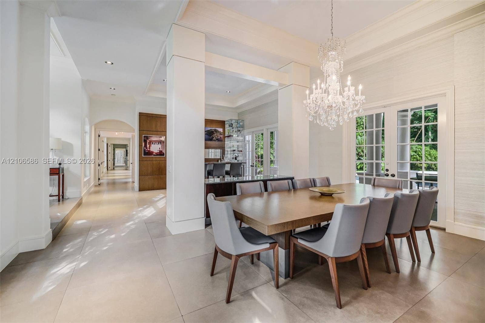 9325 SW 59th Place, Pinecrest, FL 33156 Spacious dining area featuring large-format tile flooring, tray ceilings, floor-to-ceiling columns, a crystal chandelier, and French door access to the exterior
