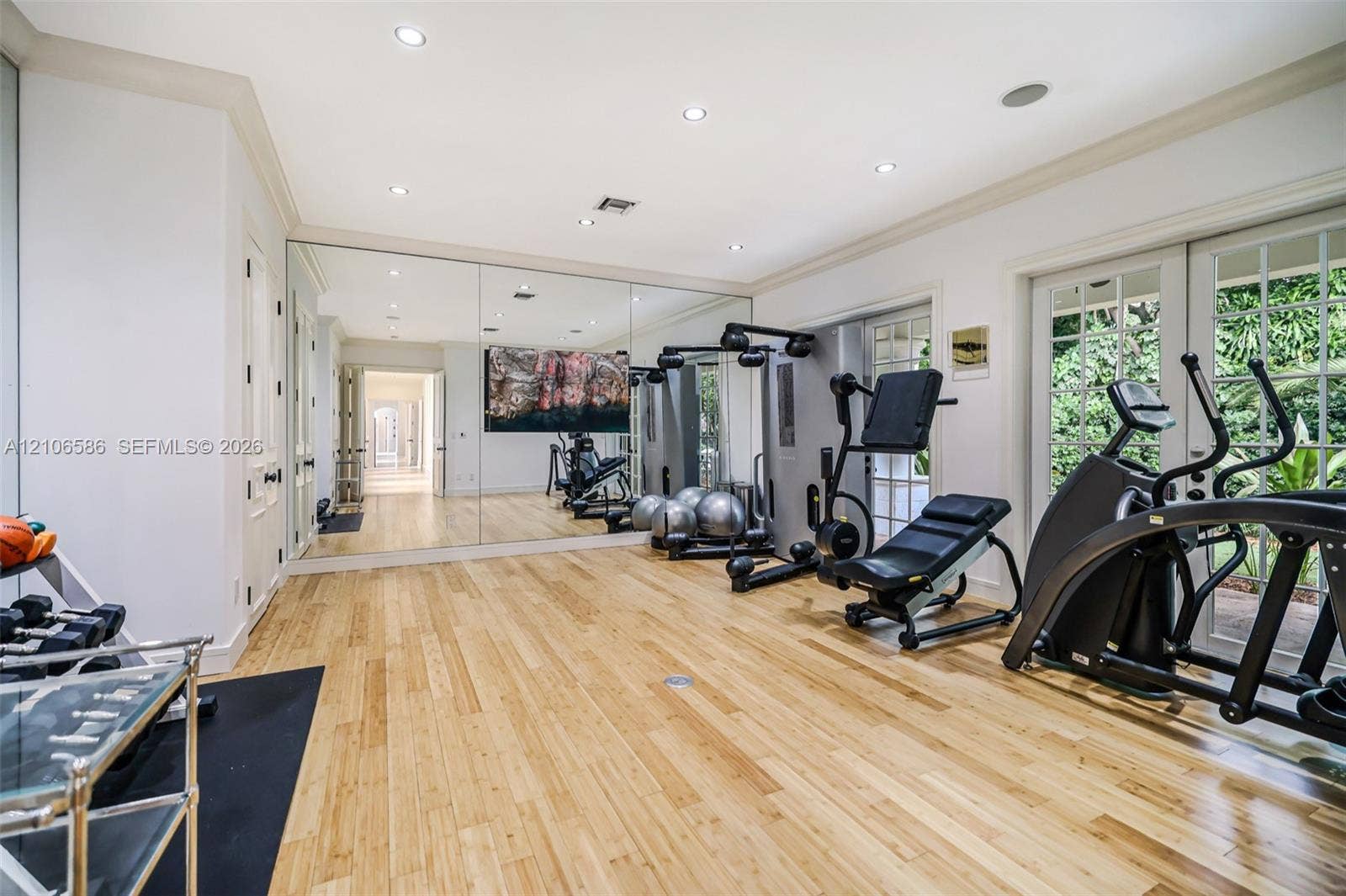 9325 SW 59th Place, Pinecrest, FL 33156 Room featuring wood-finish flooring, recessed lighting, expansive wall-to-wall mirrors, and dual sets of glass-paneled french doors