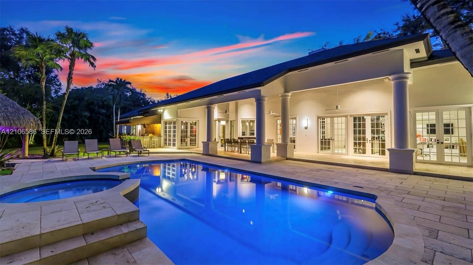 9325 SW 59th Place, Pinecrest, FL 33156 Spacious exterior featuring a covered patio with columns, stone-paved decking, a built-in swimming pool, a separate spa, and multiple sets of French doors