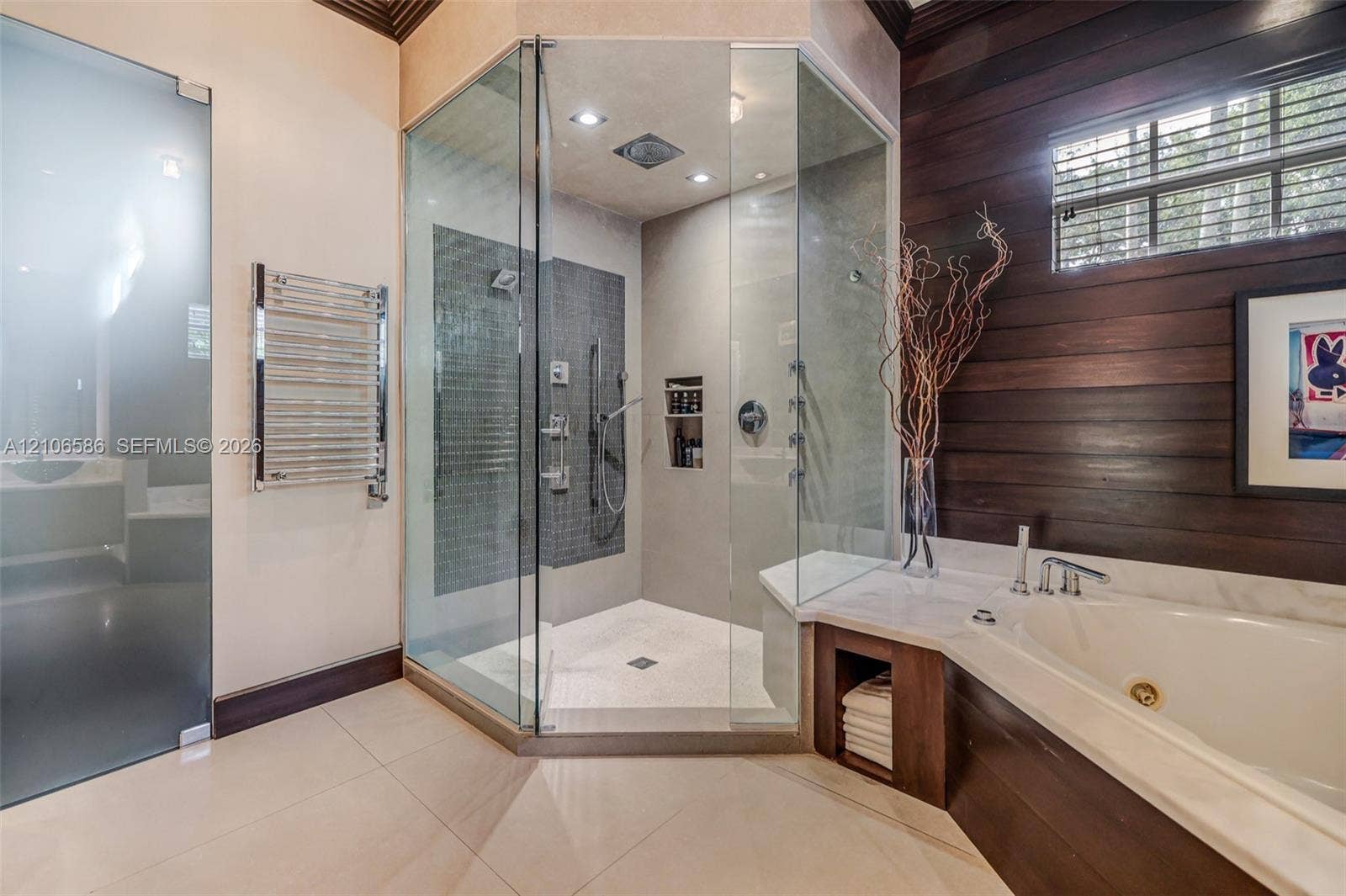 9325 SW 59th Place, Pinecrest, FL 33156 Walk-in glass shower with dual shower heads, deep soaking tub, wood-plank wall paneling, chrome heated towel rack, and large-format tile flooring