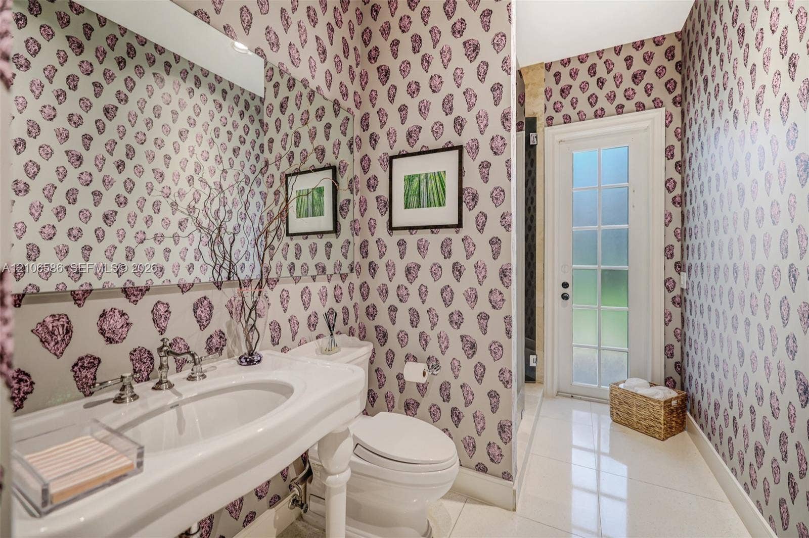 9325 SW 59th Place, Pinecrest, FL 33156 Pedestal sink with polished chrome widespread faucet, expansive wall-to-wall mirror, patterned wallpaper, and glass-paneled exterior door featuring tile flooring
