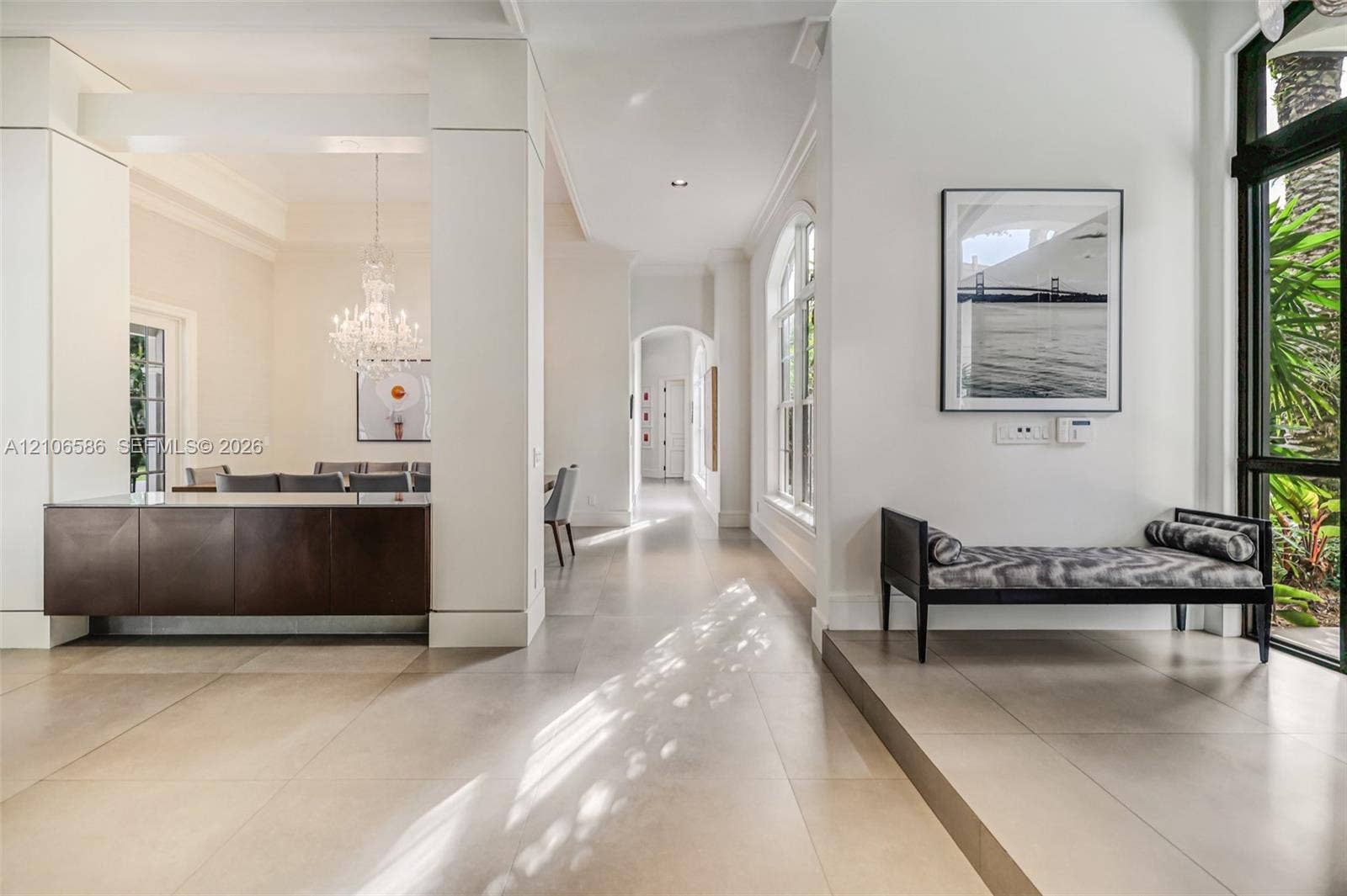 9325 SW 59th Place, Pinecrest, FL 33156 Interior space featuring large-format tile flooring, a dark-finish built-in console with a light-tone countertop, a crystal chandelier, arched architectural accents, and floor-to-ceiling windows