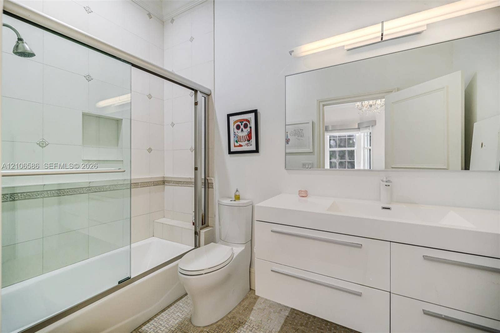 9325 SW 59th Place, Pinecrest, FL 33156 Modern bathroom featuring a high-gloss double vanity with an integrated countertop, large-format tiled walls with decorative inlay, built-in shower niche, glass shower enclosure, and linear wall-mounted lighting
