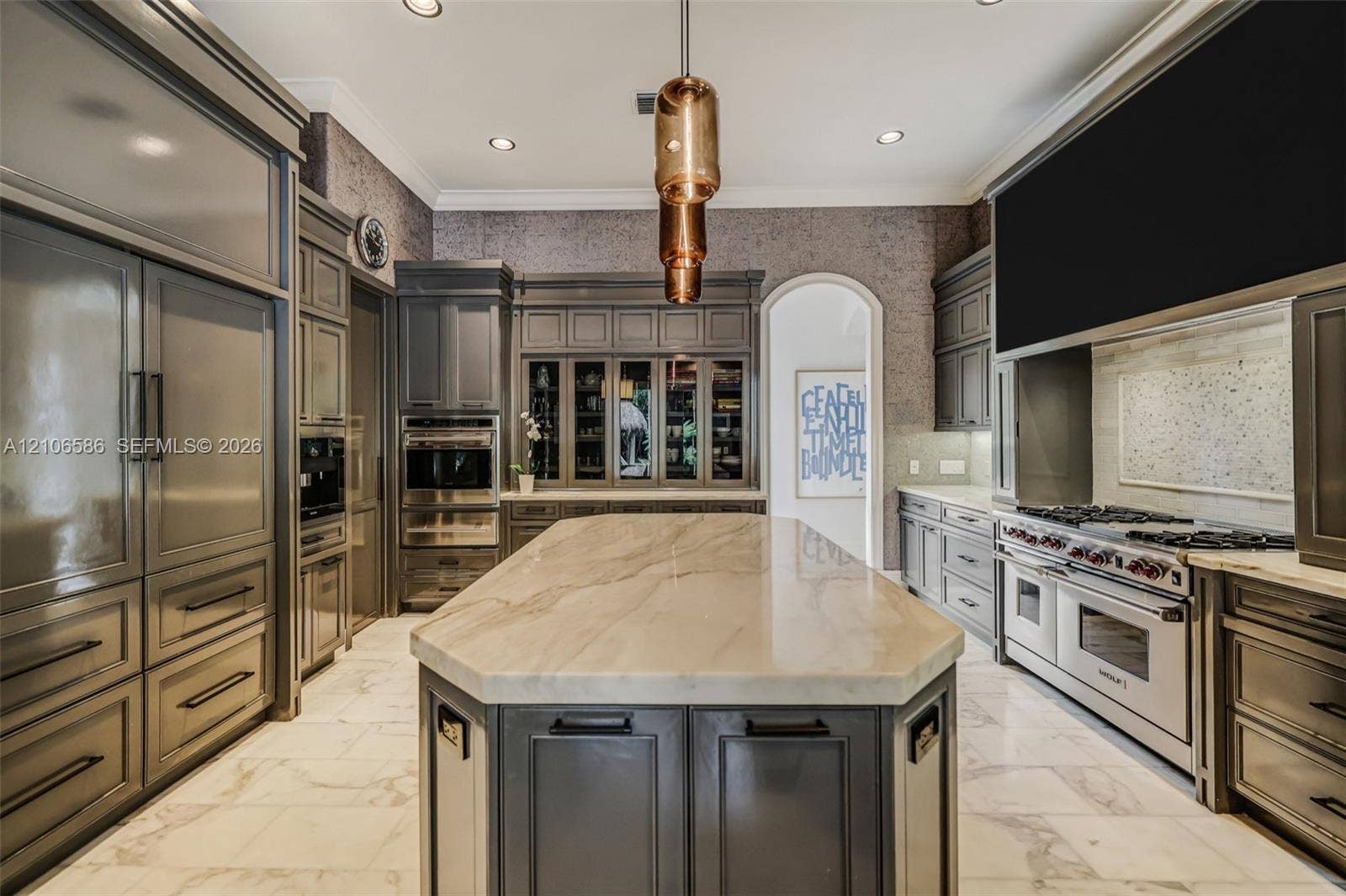 9325 SW 59th Place, Pinecrest, FL 33156 Custom cabinetry with integrated appliances, expansive central island with stone-finish countertop, professional-grade range, built-in display cabinetry, and polished stone-finish flooring
