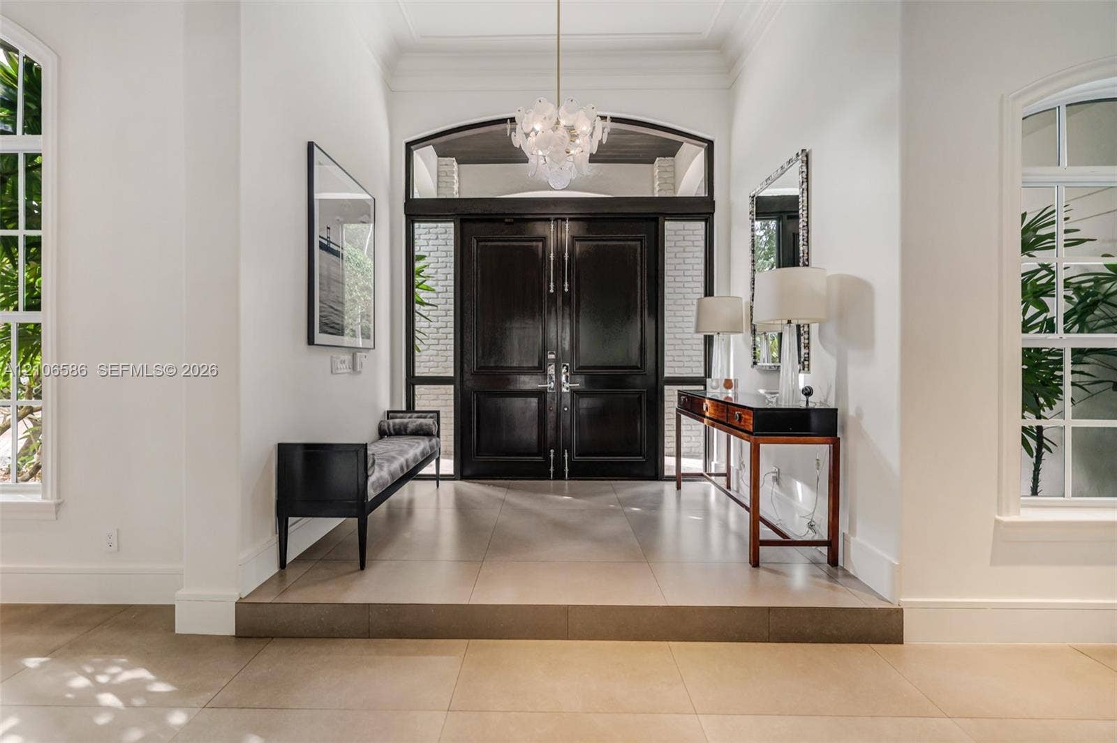 9325 SW 59th Place, Pinecrest, FL 33156 Foyer featuring large-format tile flooring, a set of double entry doors with transom window, oversized arched windows, and an ornate glass chandelier
