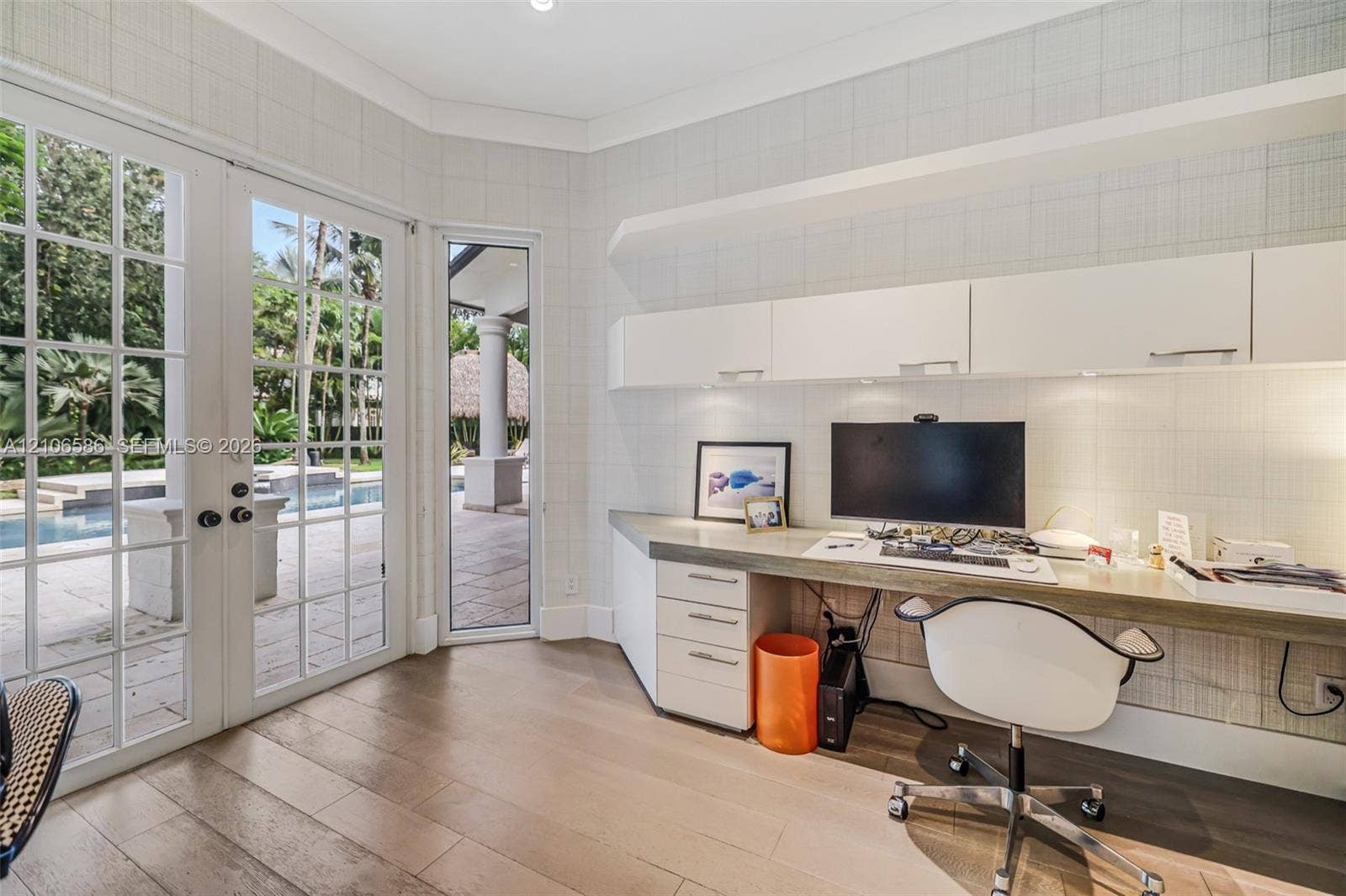 9325 SW 59th Place, Pinecrest, FL 33156 Custom built-in desk with integrated storage cabinetry, wood-finish flooring, and white paneled walls featuring multi-pane glass doors