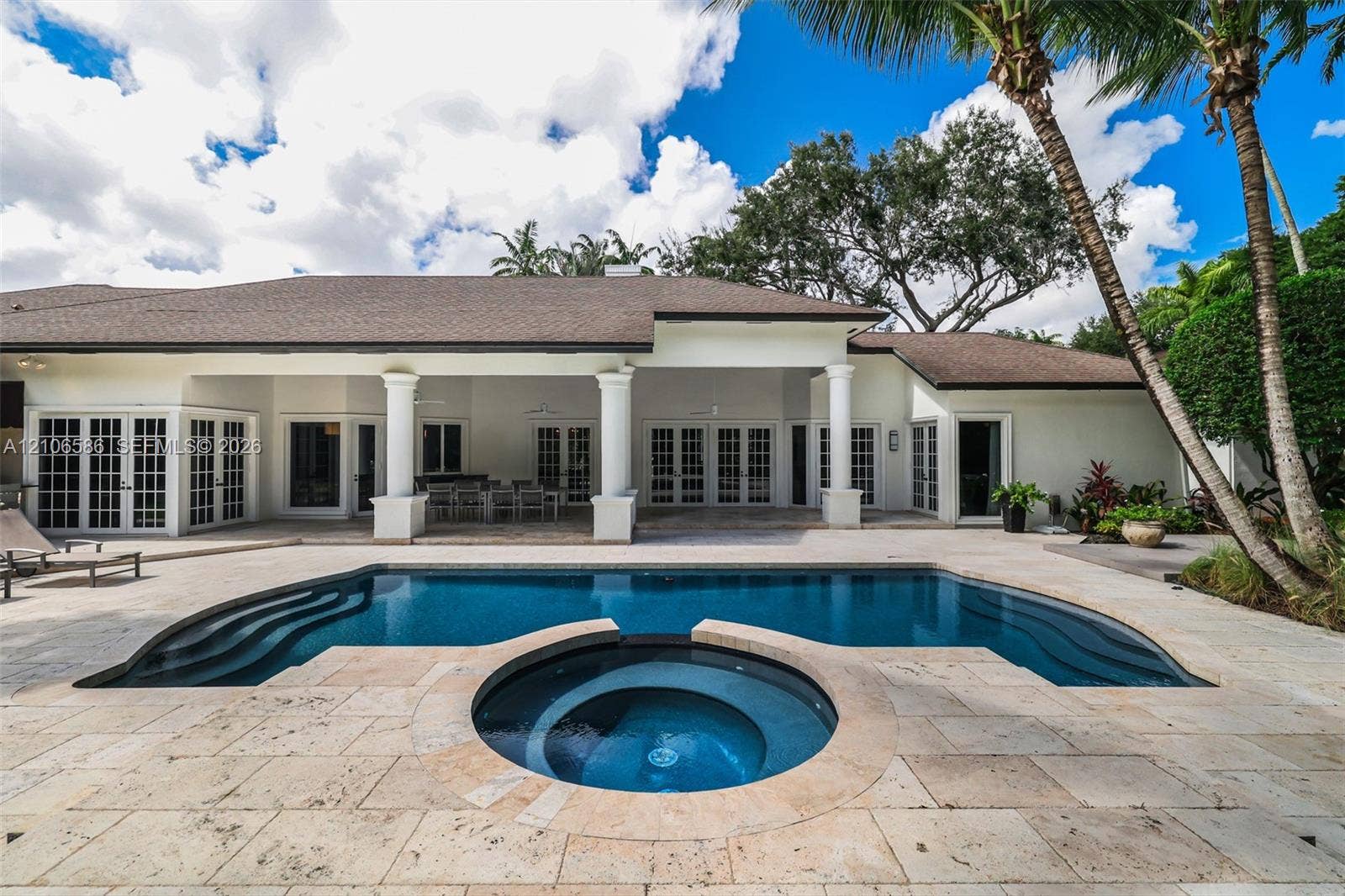 9325 SW 59th Place, Pinecrest, FL 33156 Covered patio with architectural columns, stone paver decking, and in-ground swimming pool featuring an integrated circular spa