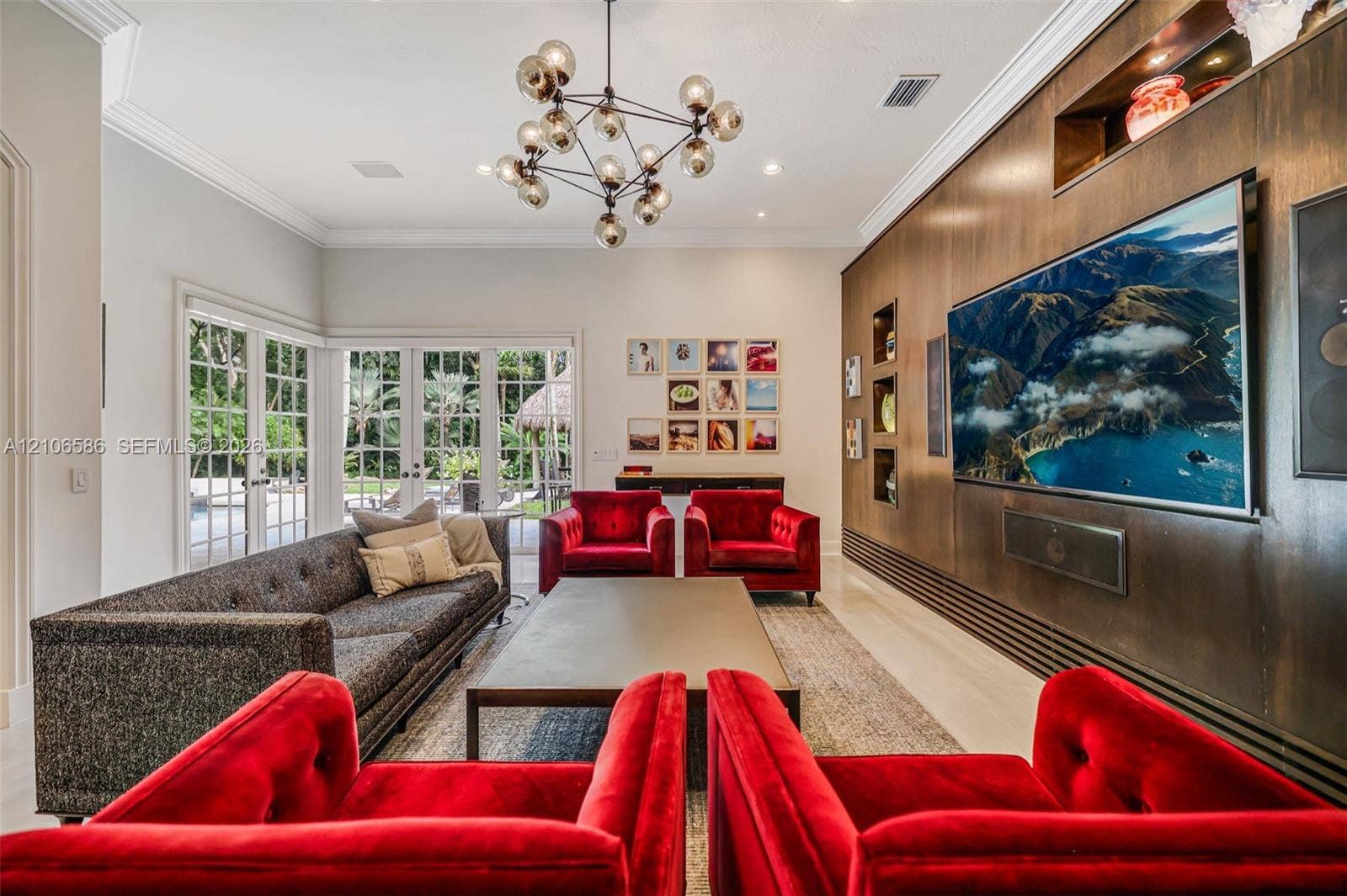 9325 SW 59th Place, Pinecrest, FL 33156 Living area featuring custom wood wall paneling with integrated shelving, multi-globe chandelier, recessed lighting, and full-height glass paneled doors