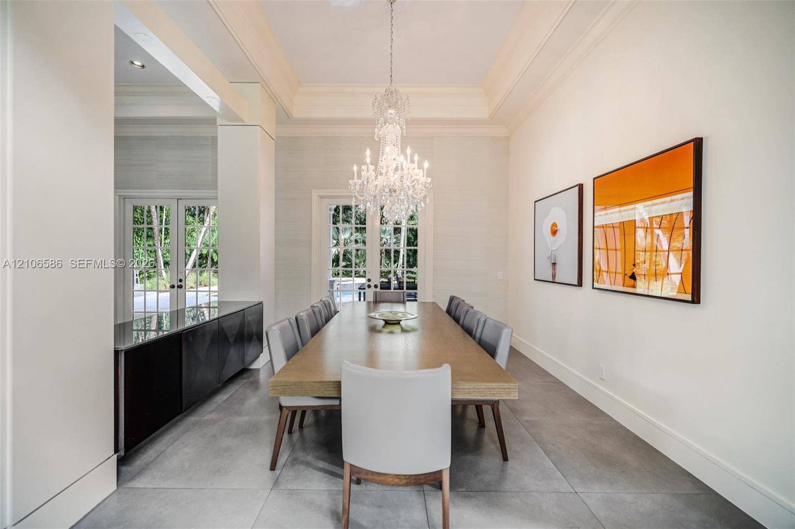 9325 SW 59th Place, Pinecrest, FL 33156 Formal room featuring a tray ceiling, crystal chandelier, large-format tile flooring, built-in cabinetry with a stone countertop, and multi-pane glass doors