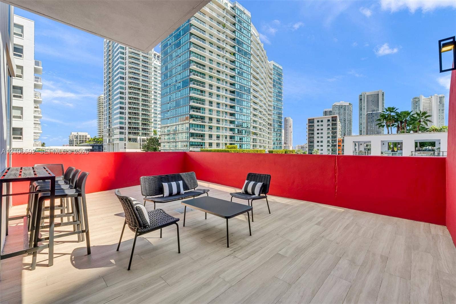 90 NE 32, #612, Miami, Miami, FL 33127 Open-air balcony featuring wood-finish tile flooring, solid red privacy walls, and a wall-mounted light fixture