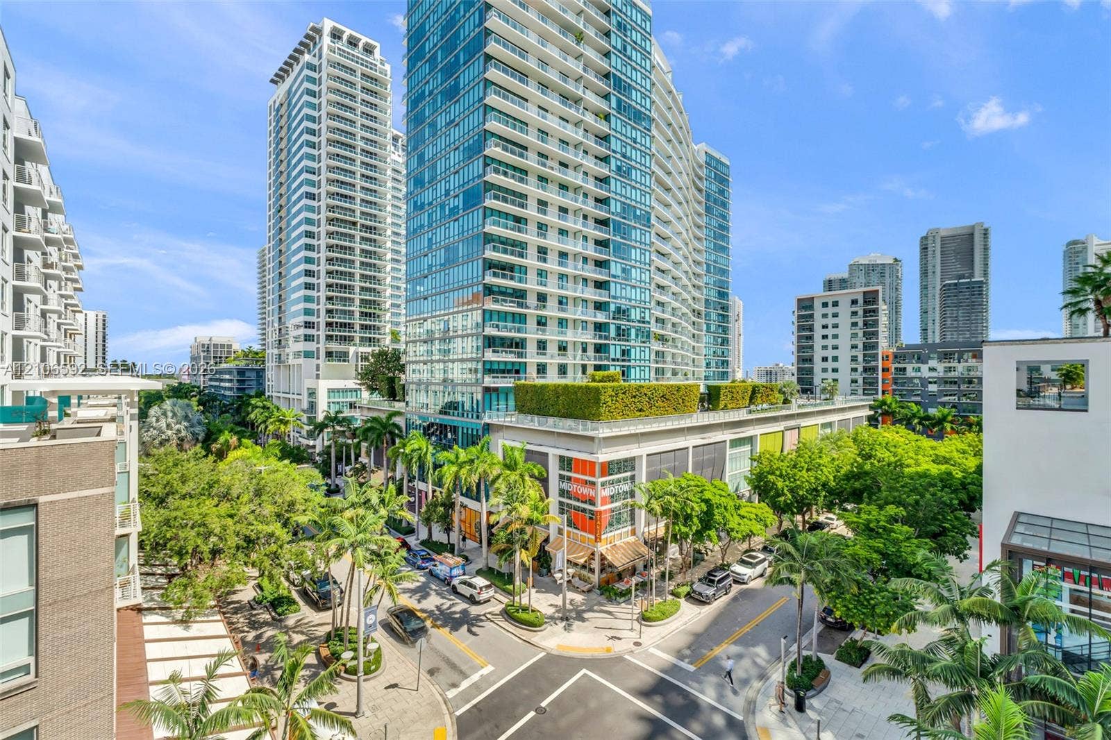 90 NE 32, #612, Miami, Miami, FL 33127 High-rise exterior featuring floor-to-ceiling glass paneling, multi-level structural design, manicured rooftop greenery, and ground-level storefronts with metal framing